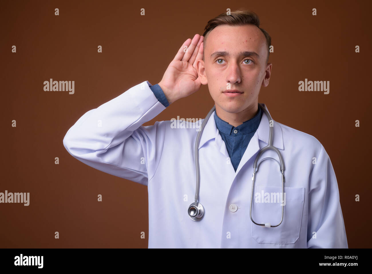 Jungen gutaussehenden Mann Arzt gegen braunen Hintergrund Stockfoto
