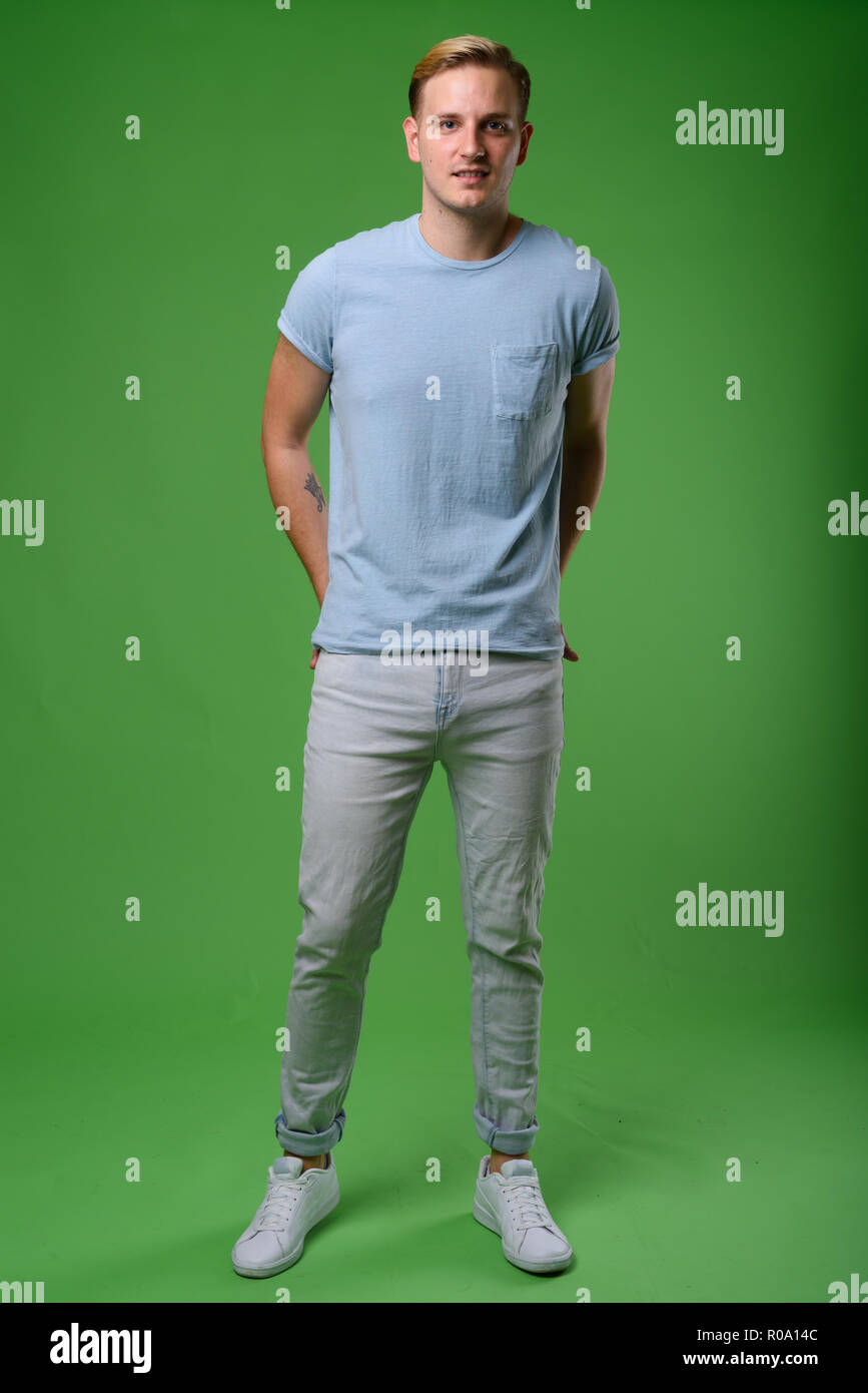 Junger stattlicher Mann mit blonden Haaren gegen grüner Hintergrund Stockfoto