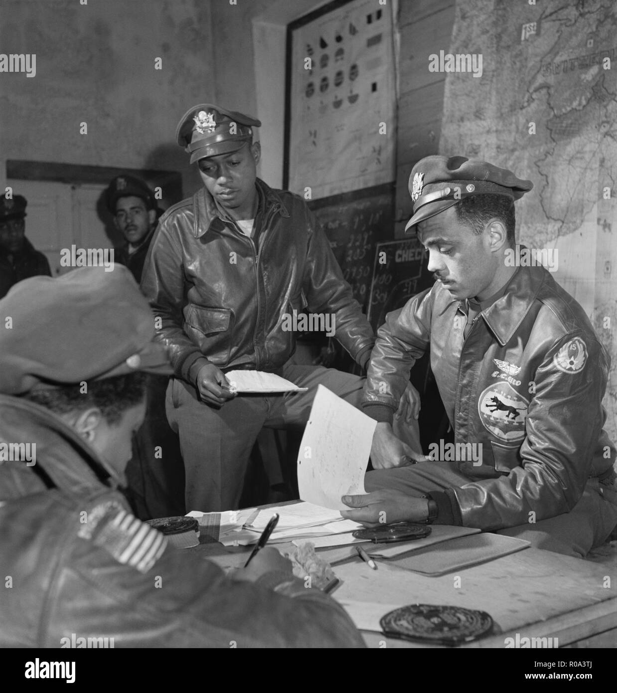 Tuskegee Airmen an Briefing in Air Base, Woodrow W. Crockett, stehend in der Mitte, Edward C. Gleed, Lawrence, KS, Klasse 42-K, Gruppe Operations Officer, sitzt auf der rechten, und nicht identifizierte Flieger sitzt auf der linken Seite, Ramitelli, Italien, Toni Frissell, März 1945 Stockfoto