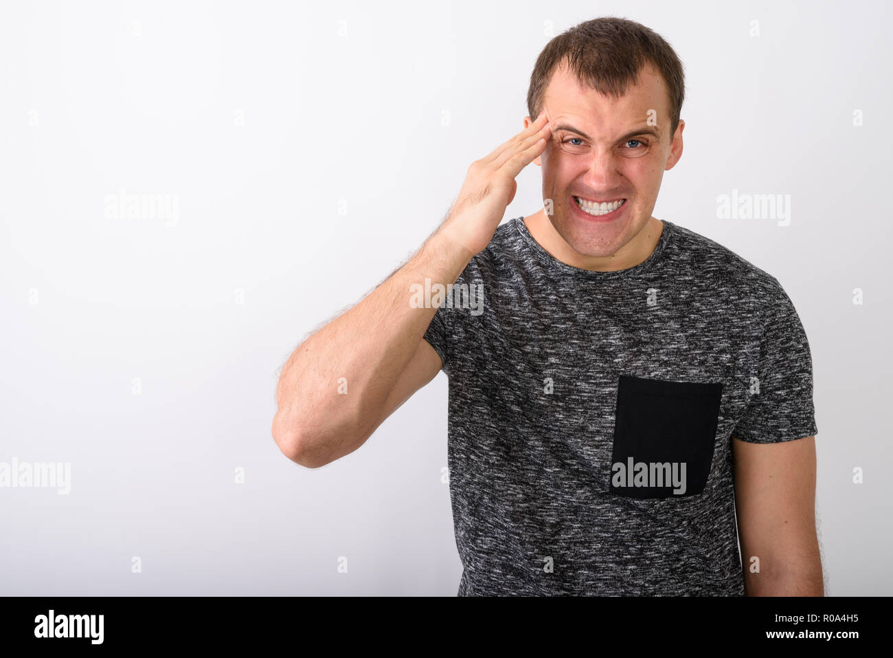 Studio geschossen von wütenden jungen muskulösen Mann mit Kopfschmerzen gegen Stockfoto