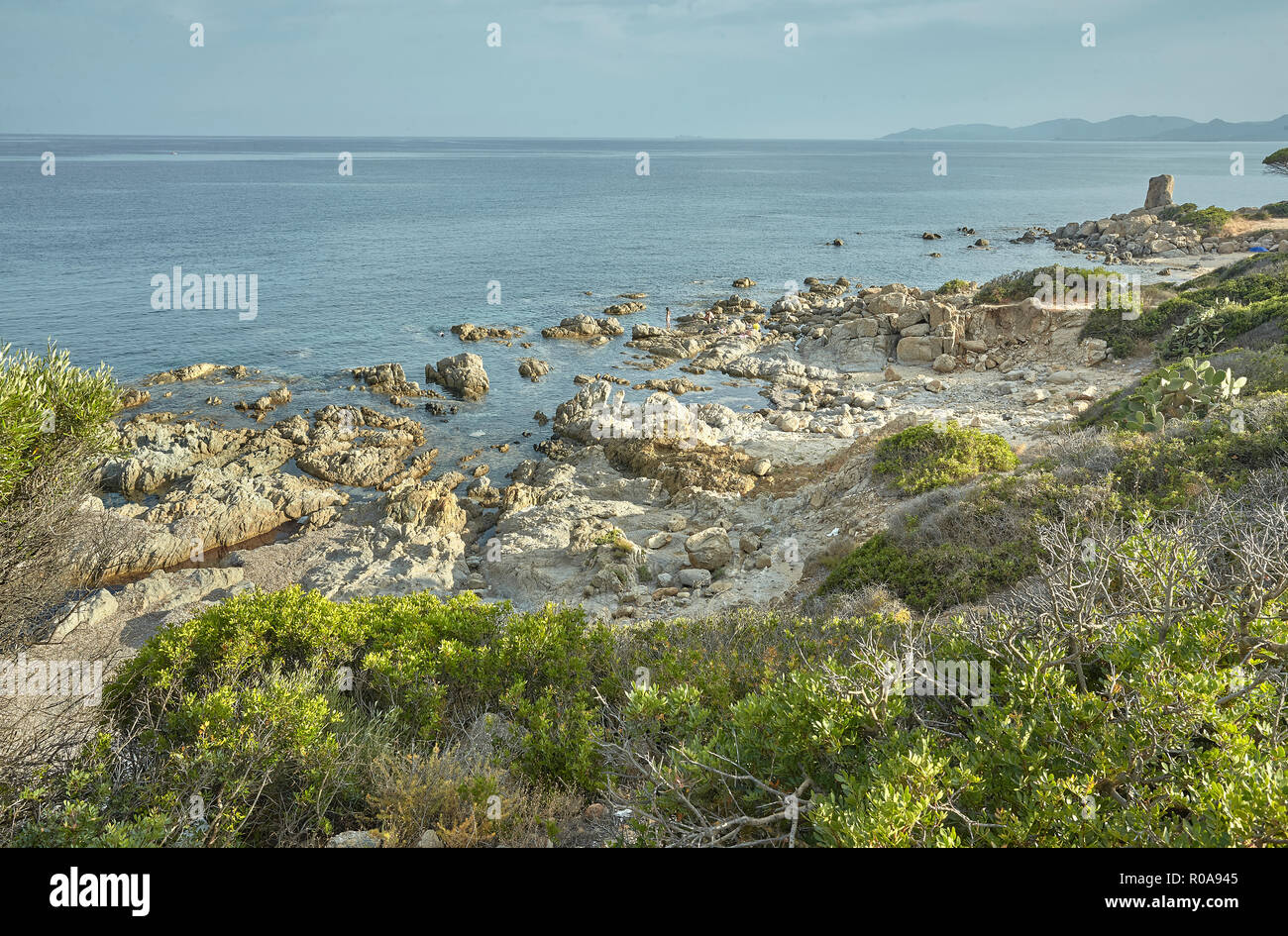 Steine und Felsen, die typisch für die südliche Küste von Sardinien in Italien durch das Meer und die typischen Strauch Vegetation dieser Gebiet umgeben. Stockfoto