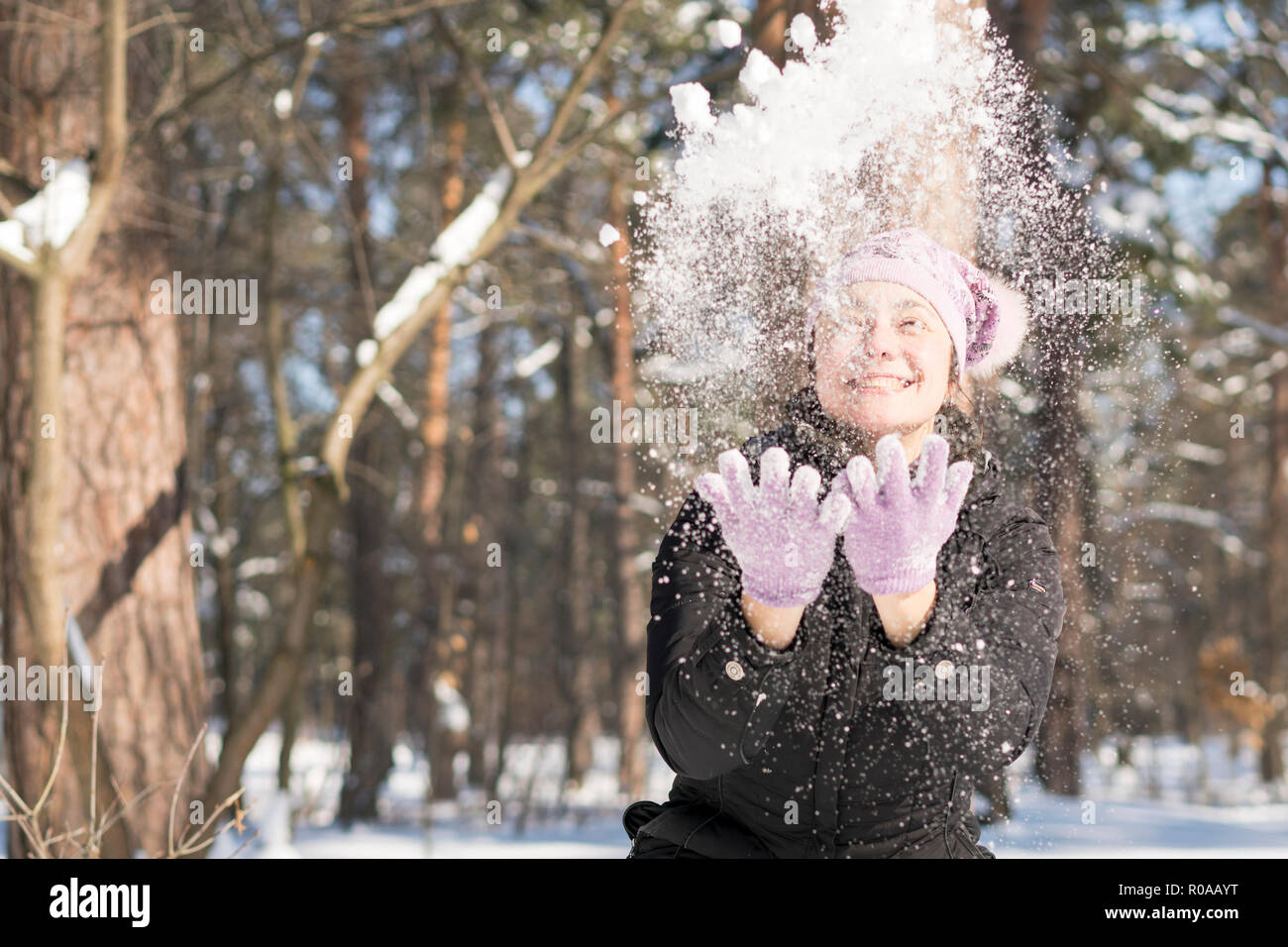 Mädchen wirft Schnee. Porträt der schönen Mädchen werfen Schnee im Winter. Glückliche junge Frau spielt mit einem Schnee im sonnigen Wintertag. Stockfoto