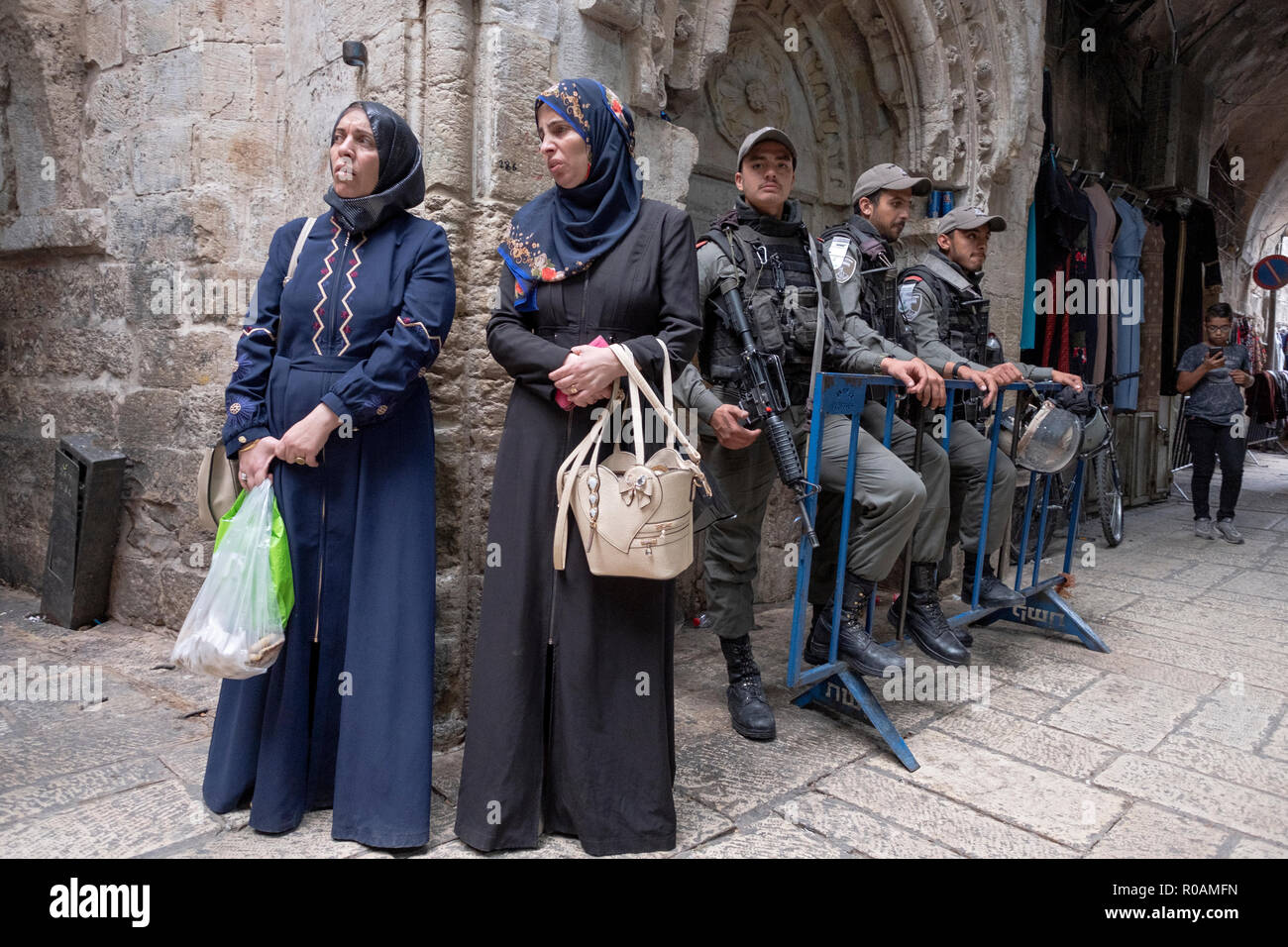 Bewaffnete israelische Soldaten in der Nähe von muslimischen arabischen Frauen Einkaufen in der Altstadt von Jerusalem in Israel. Stockfoto