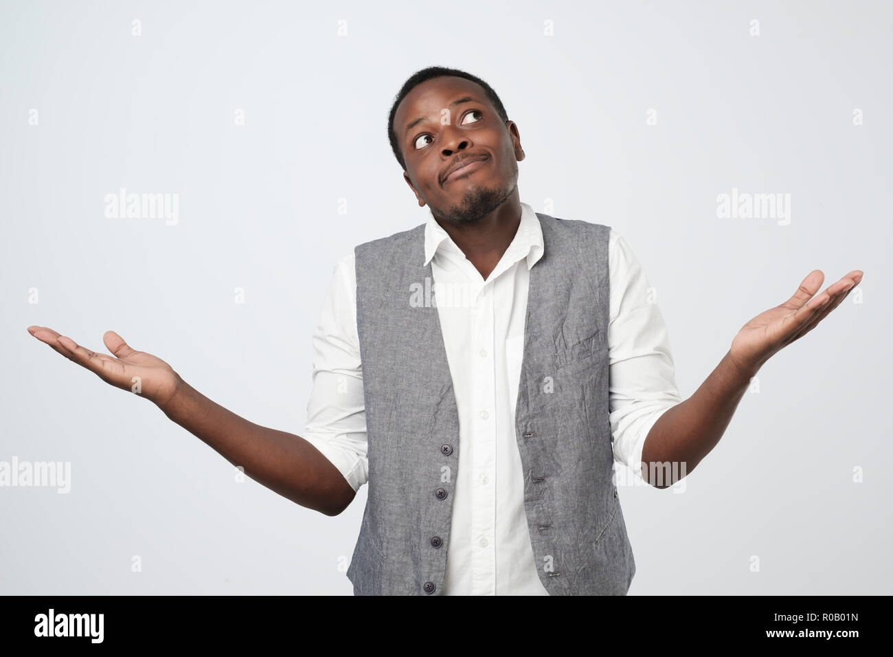 Junge afrikanische Mann im blauen Hemd zu einem Verlust, hilflose Geste mit Arm und Hand Stockfoto