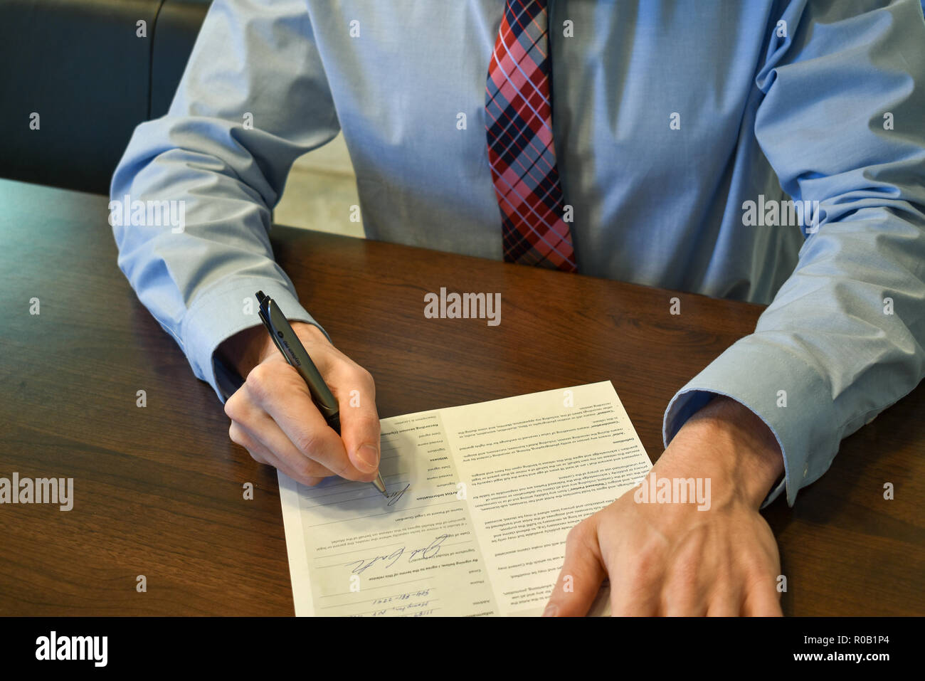 Die Unterzeichnung eines Papier am Schreibtisch Stockfoto