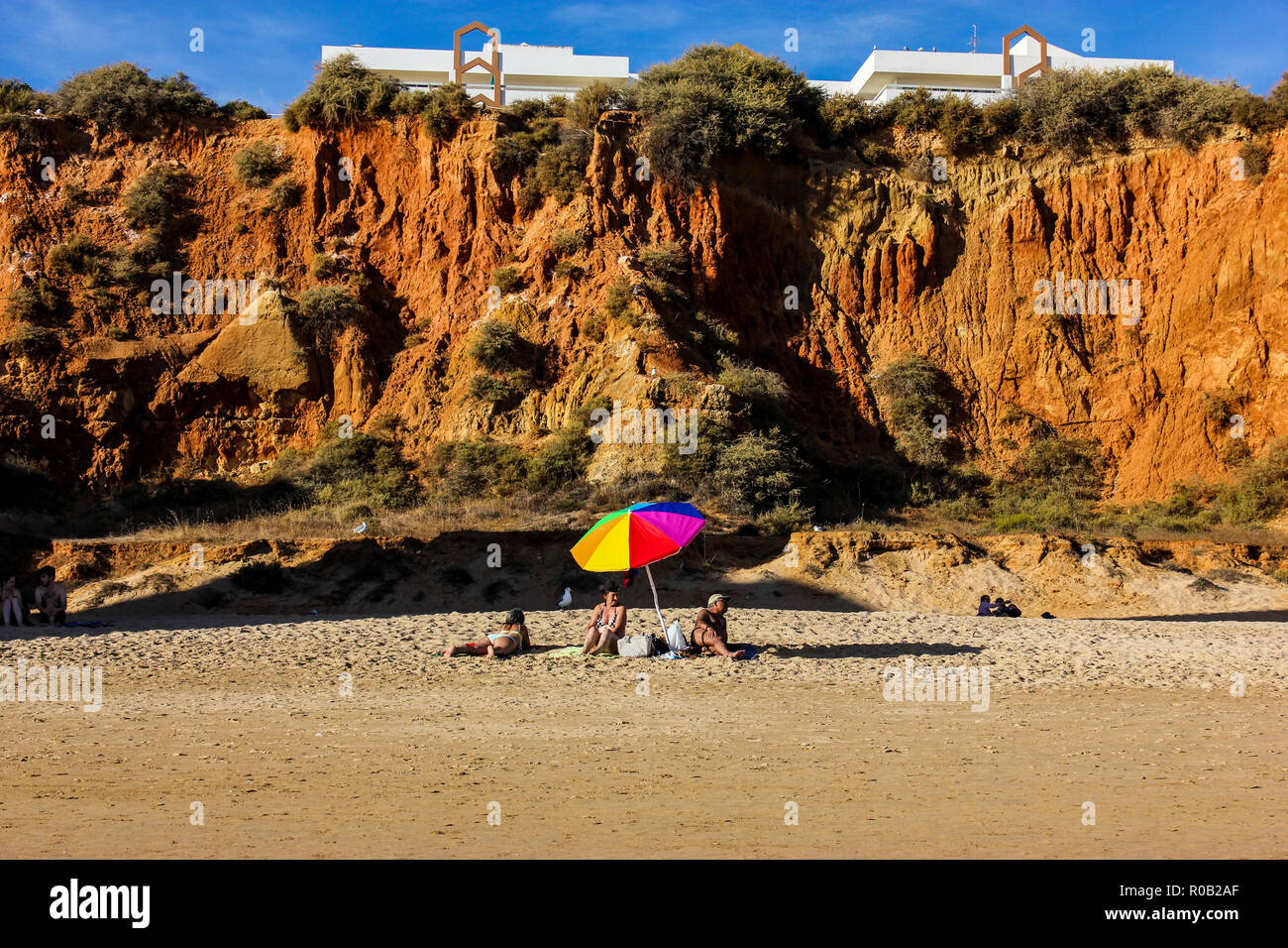 Familie ruht auf dem Strand, unter dem bunten Regenschirm, sonnigen Sommertag, keine Sorgen Stockfoto