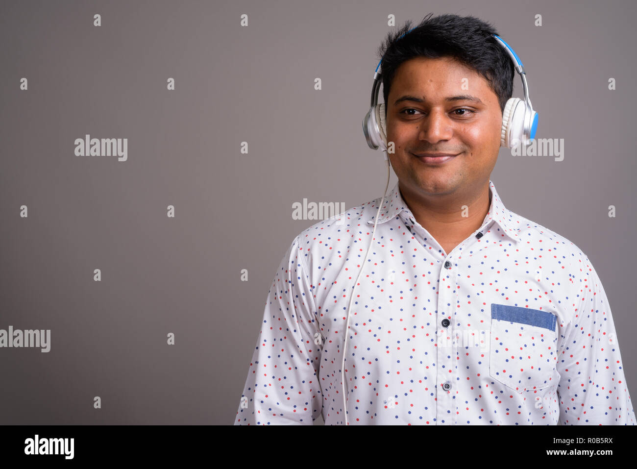 Junge indische Geschäftsmann Musik gegen Grau backgro Stockfoto