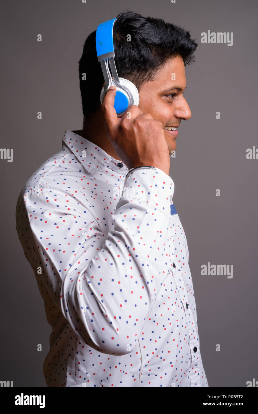 Junge indische Geschäftsmann Musik gegen Grau backgro Stockfoto