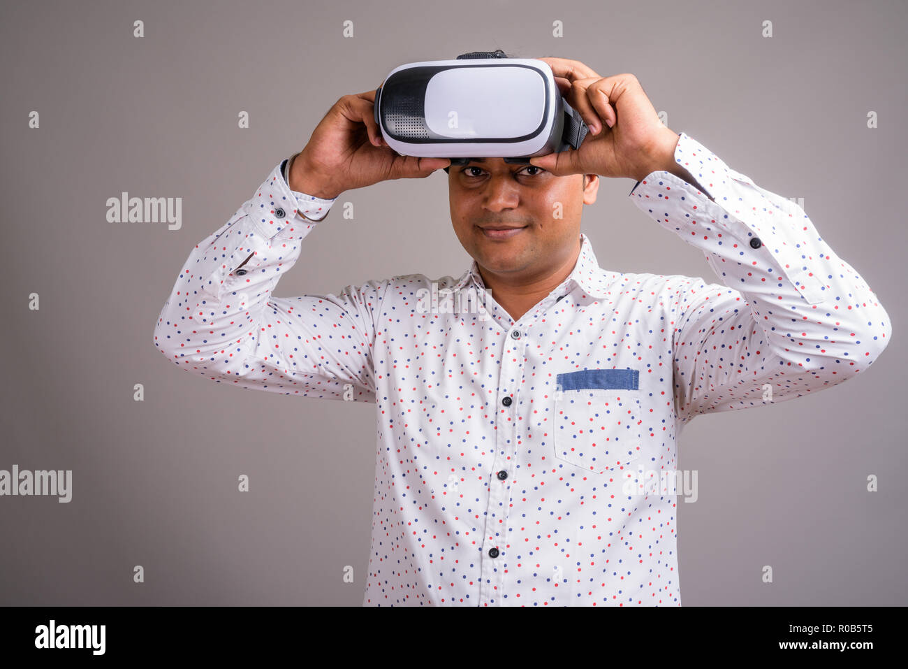 Junge indische Geschäftsmann mit Virtual reality Headset gegen g Stockfoto