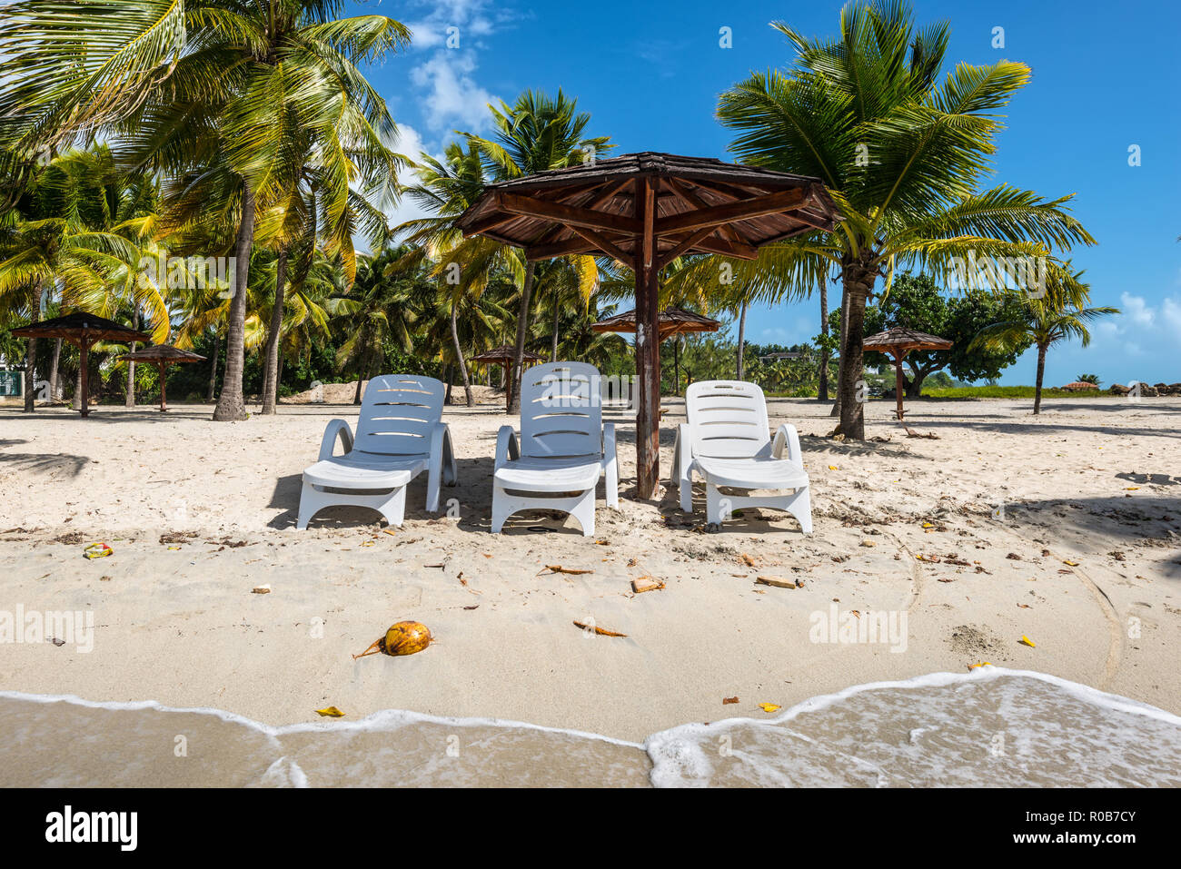 Ferienhäuser Konzept - drei Stühle und hölzerne Palapa Sonnendach Sonnenschirm am tropischen Strand - der Karibikinsel Guadeloupe Stockfoto