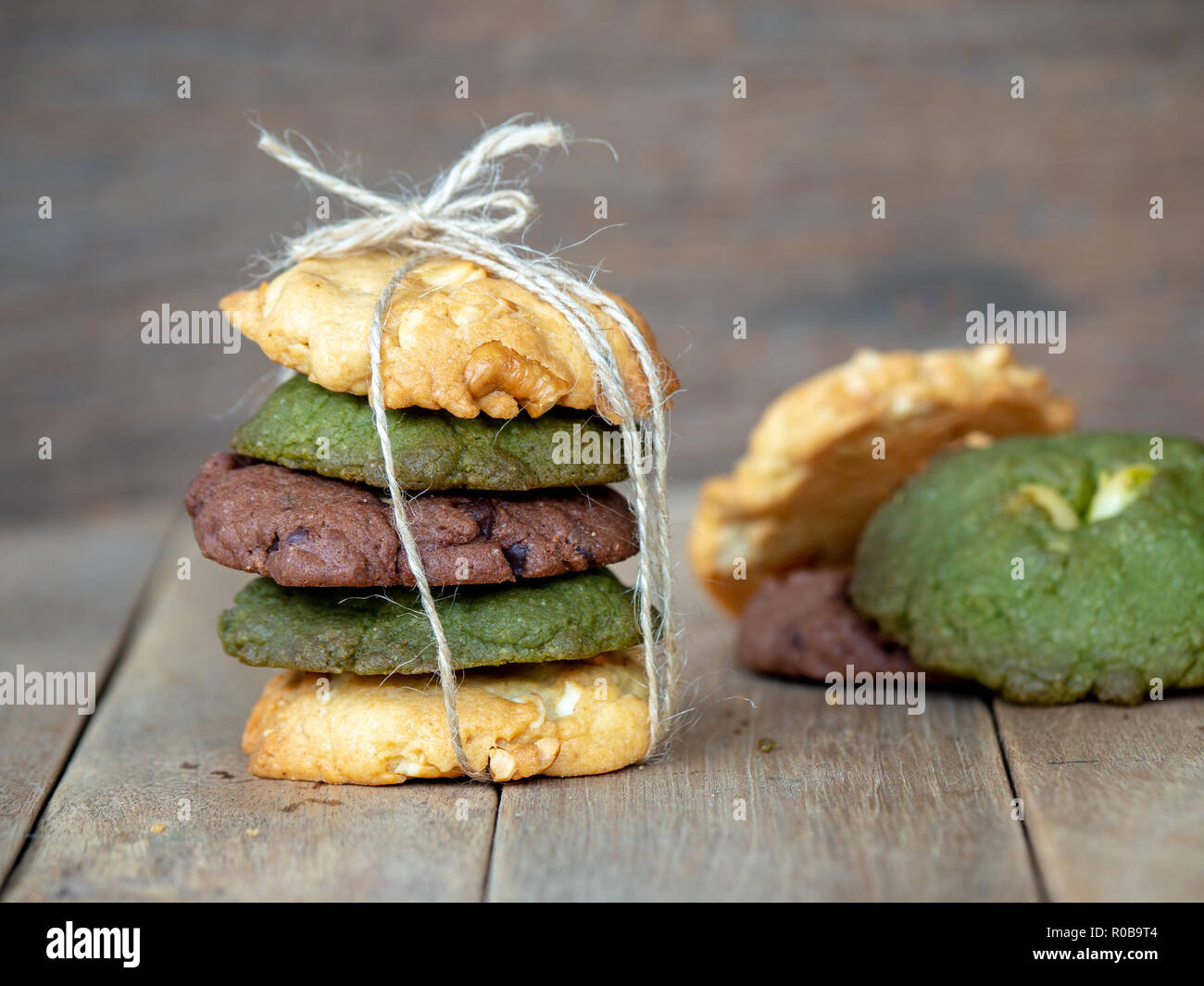 Mehrere Farbe cookies inclusive Erdnussbutter, grüner Tee und Cookies Chocolate Chip Cookies. Durch die wechselnden Farben auf Holz Tisch gelegt. Stockfoto