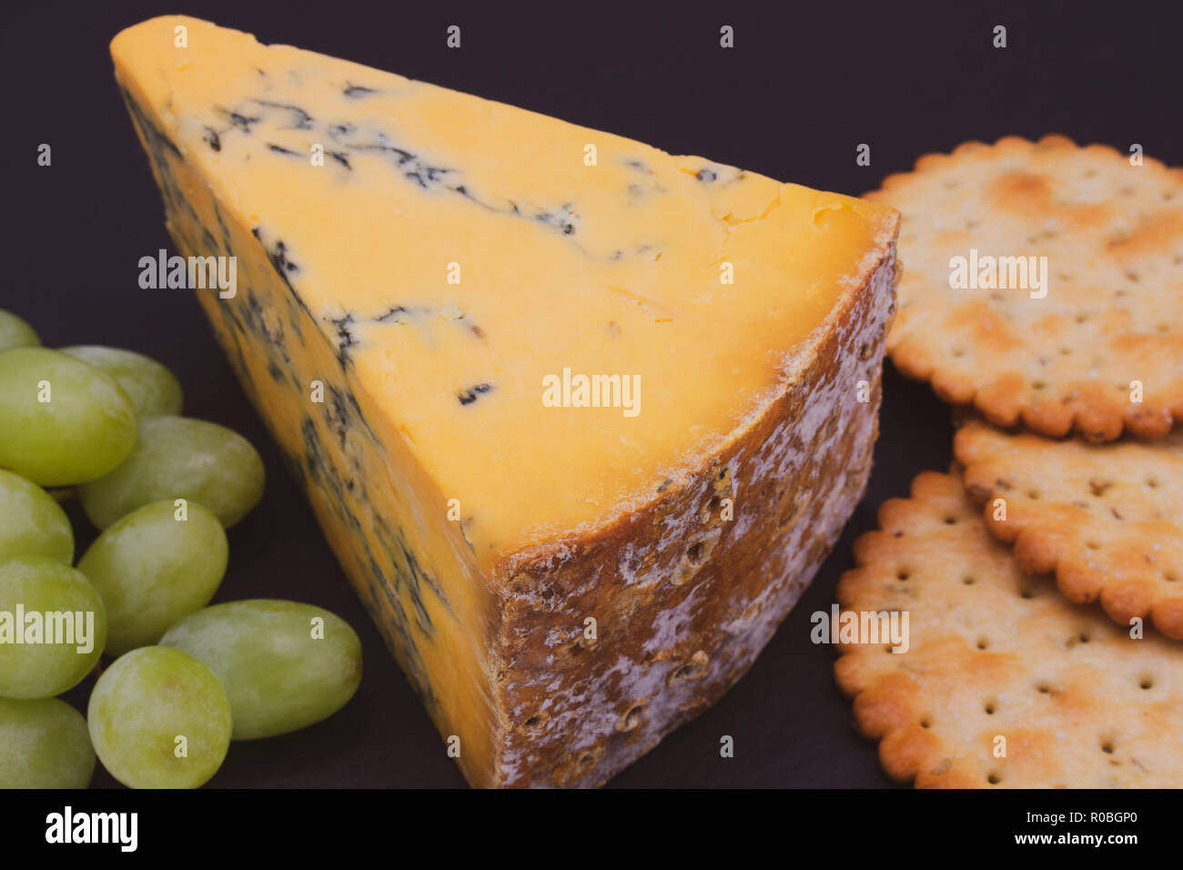 Ein Keil von Shropshire Blue Käse mit Crackern und Trauben Stockfoto