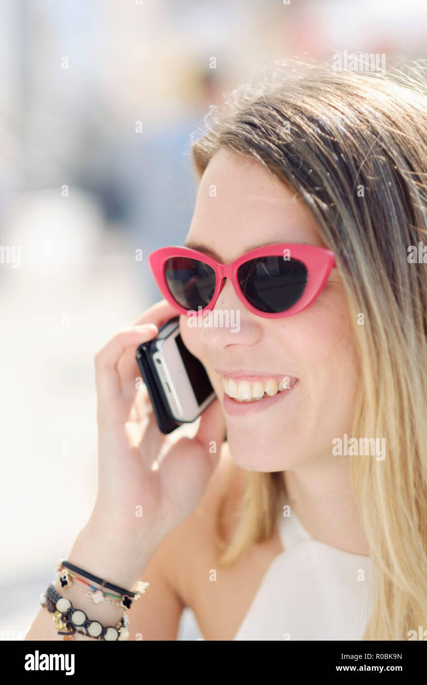 Eine junge holländische (Kaukasisch) Frau mit ihrem Mobiltelefon in der Straße an einem sonnigen Tag Stockfoto