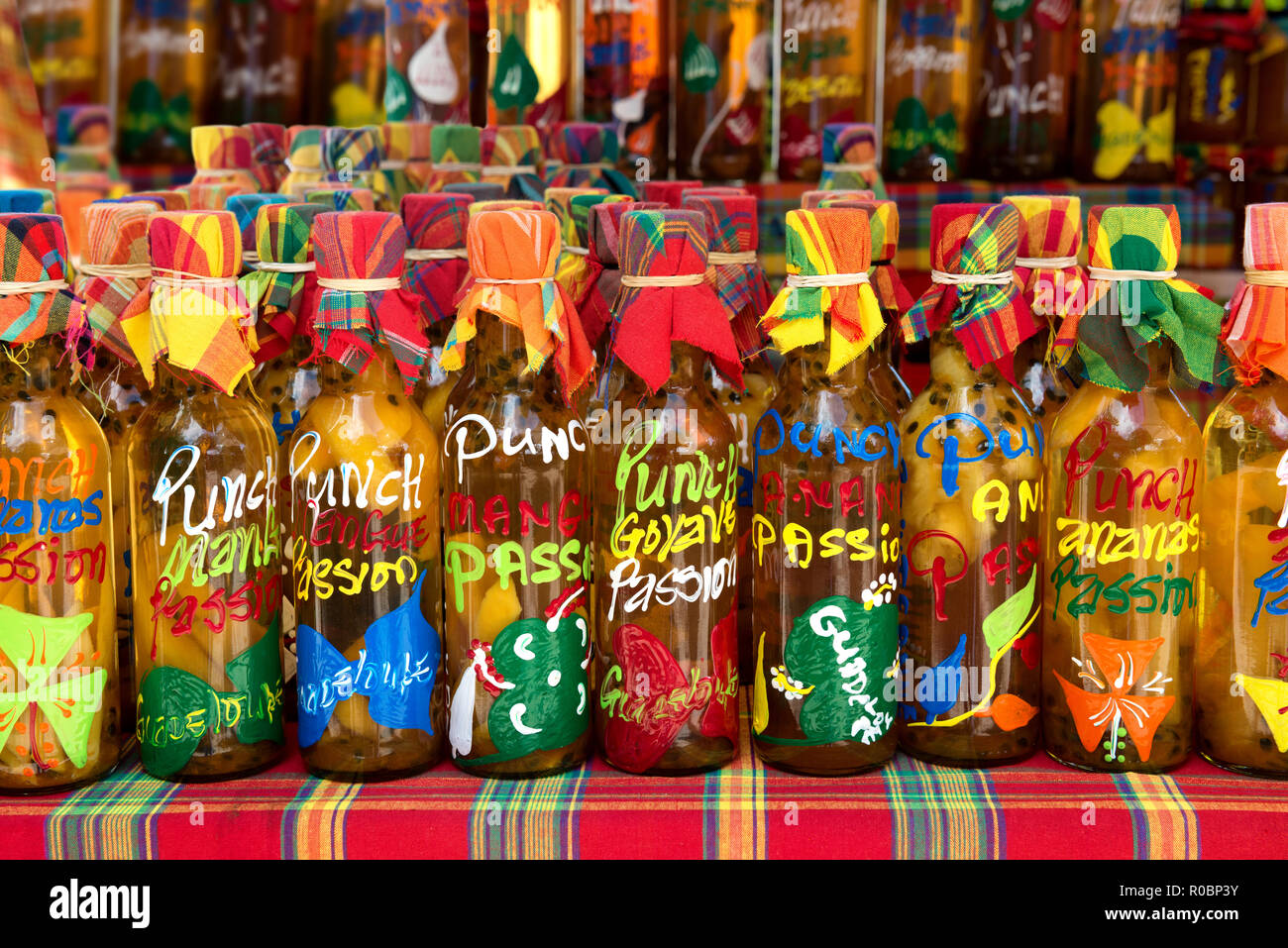 Viele verschiedene farbige Punch (Rum und tropische Früchte) Flaschen in einer Reihe auf einem typischen Markt, Guadeloupe, French West Indies. Stockfoto
