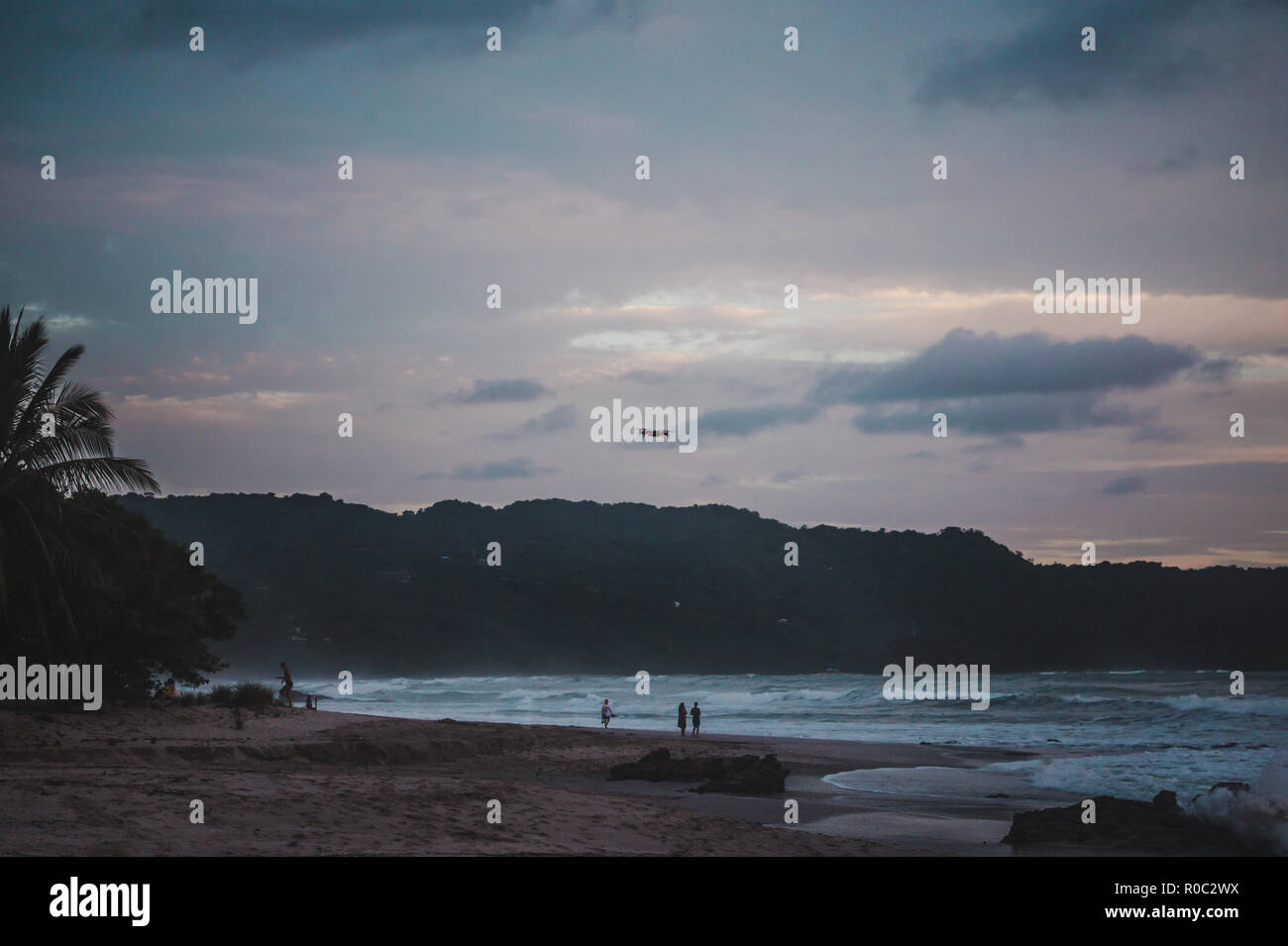 Drohne fliegt über den langen Sandstrand Paradise Strand von Playa del Carmen, Santa Teresa, Costa Rica bei einem farbenfrohen Sonnenuntergang Stockfoto