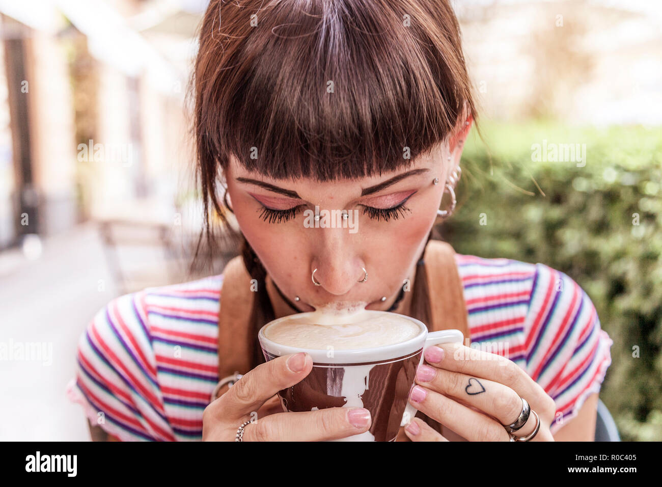 Junge Frau mit blauen Augen ihre Lippen mit Sahne dirty beim Trinken einen italienischen Cappuccino Stockfoto