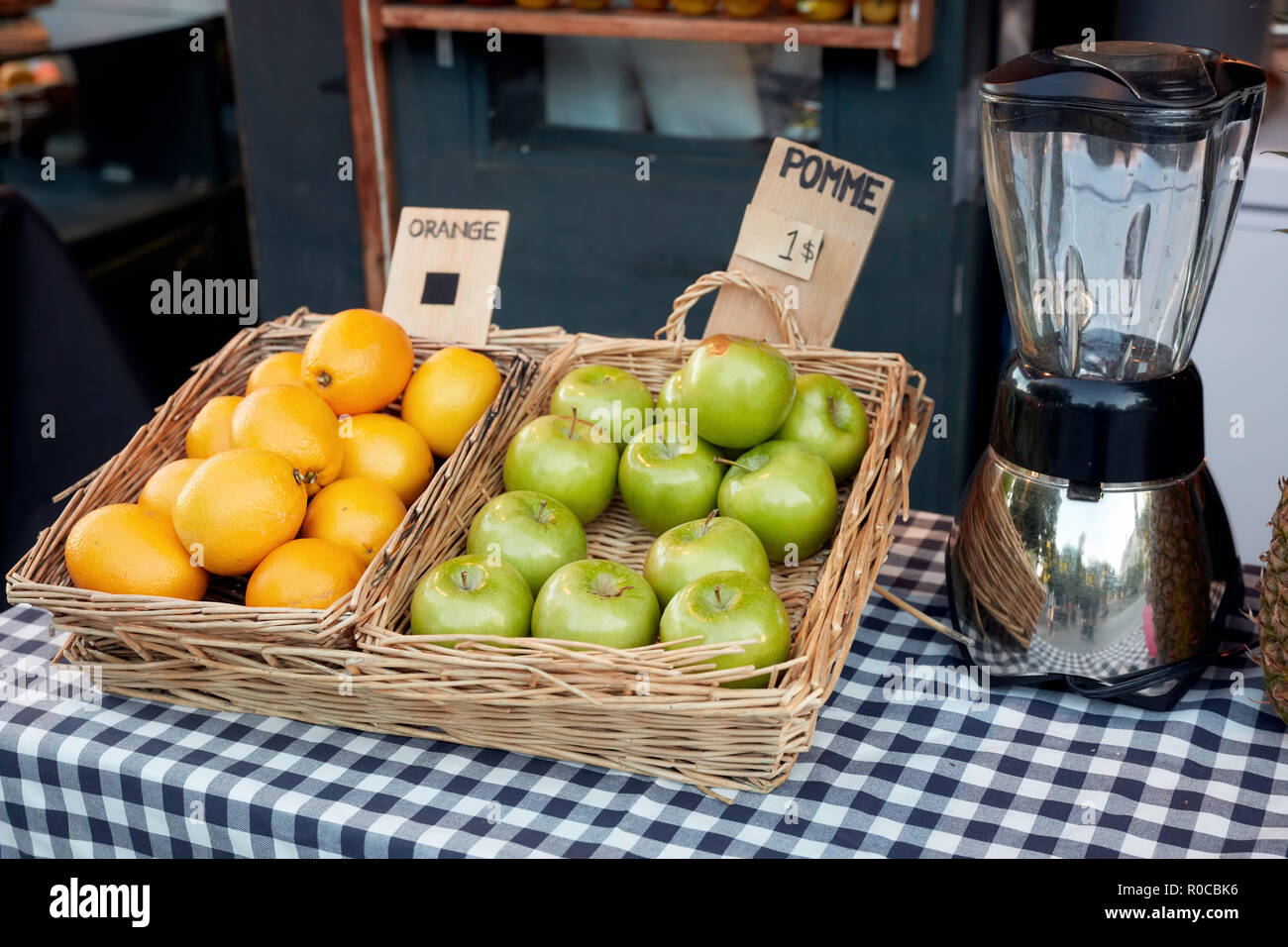 Apfel und Orange in die Körbe und ein Mixer auf der Theke von outdoor Saft bar. Preis tags sind in französischer Sprache. Stockfoto