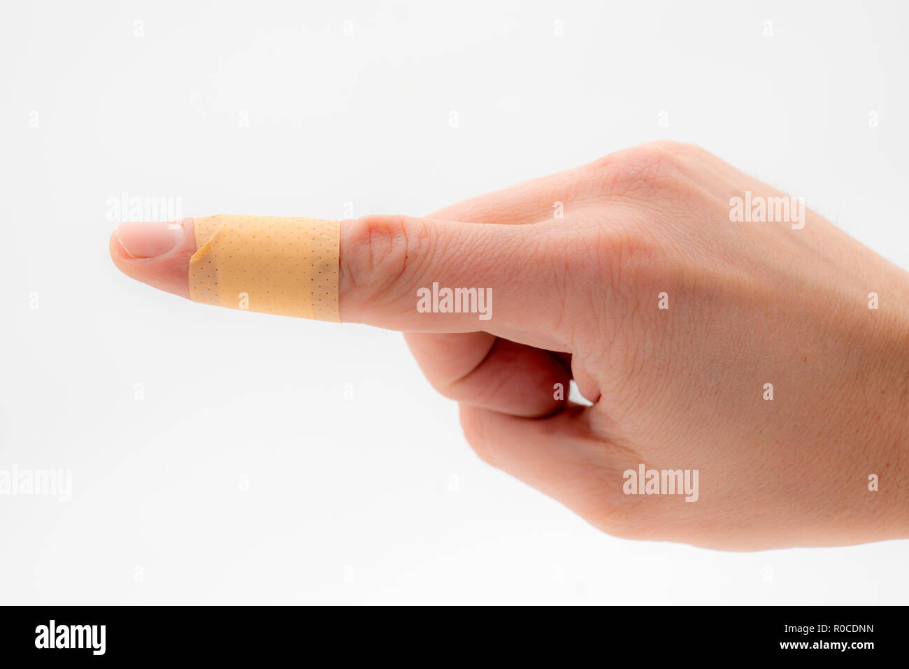 Eine Hand mit einem Patch auf dem Zeigefinger, vor einem weißen Hintergrund isoliert. Stockfoto