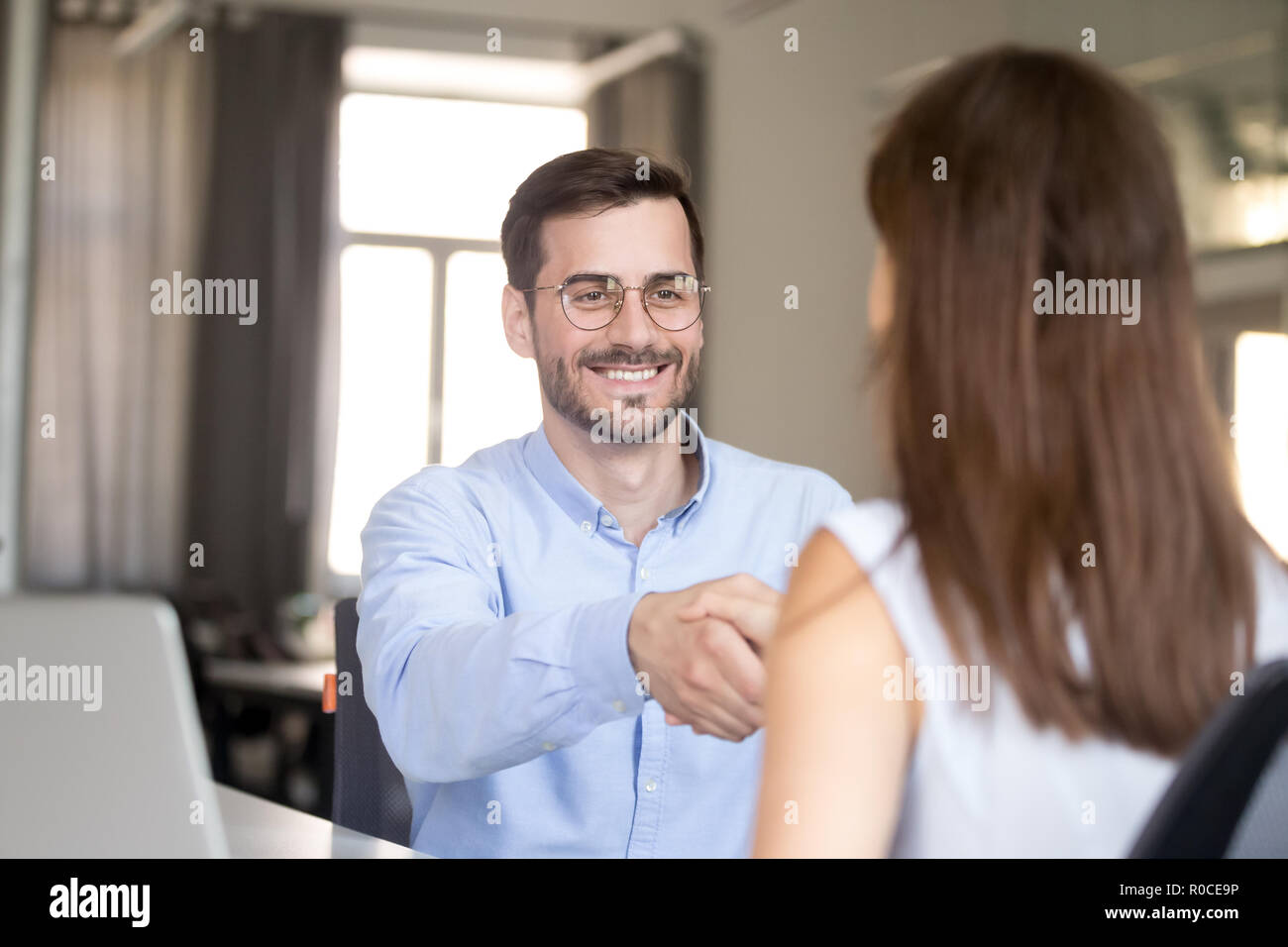 Freundlich lächelnd Geschäftsmann handshaking Frau beim Vorstellungsgespräch, Stockfoto