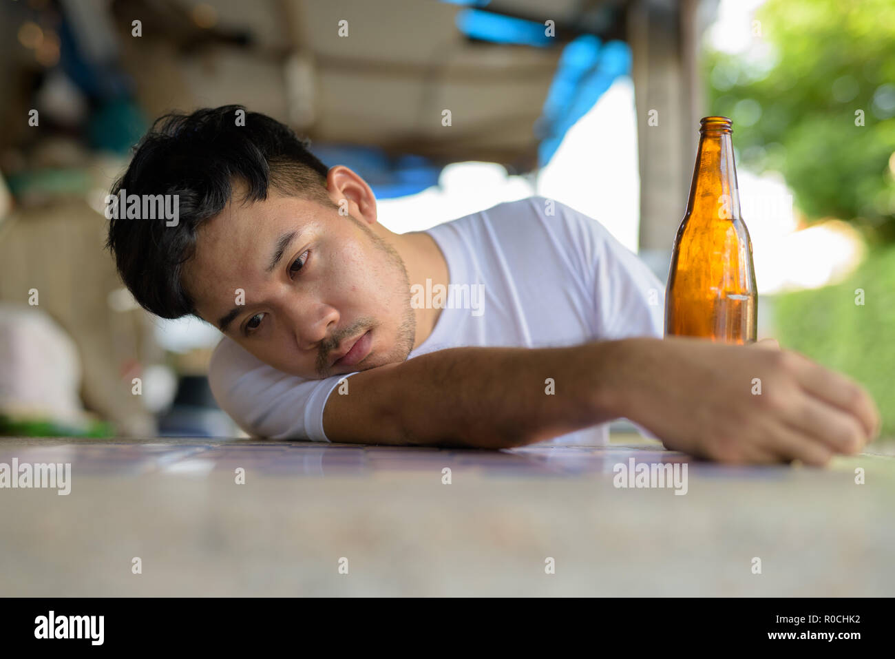 Junge asiatischer Mann betrunken auf der Straße draußen Stockfoto