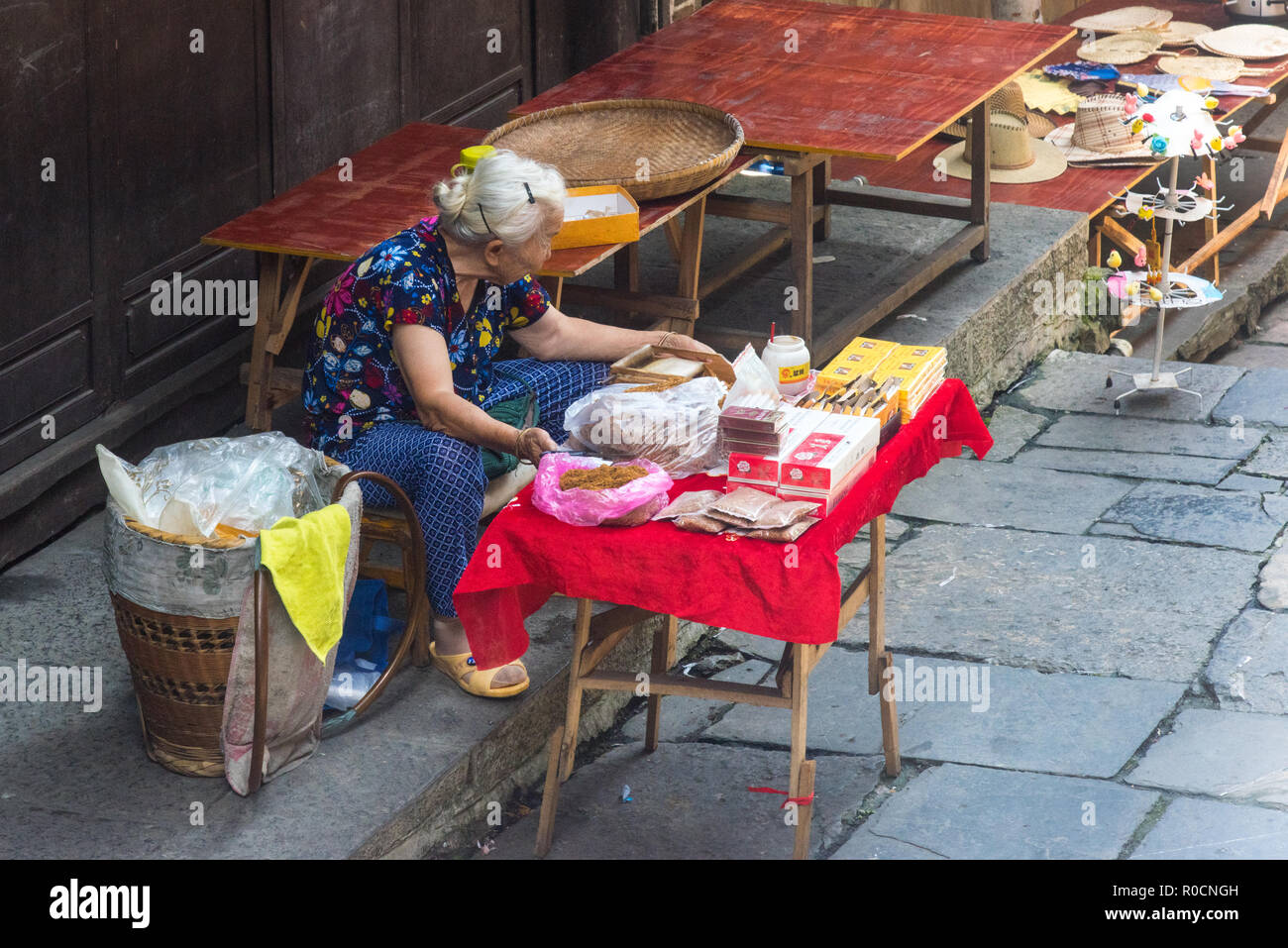 FURONG, Hunan, China, 10. JULI 2018: Ältere Frau herstellen und verkaufen von Zigaretten, Stockfoto