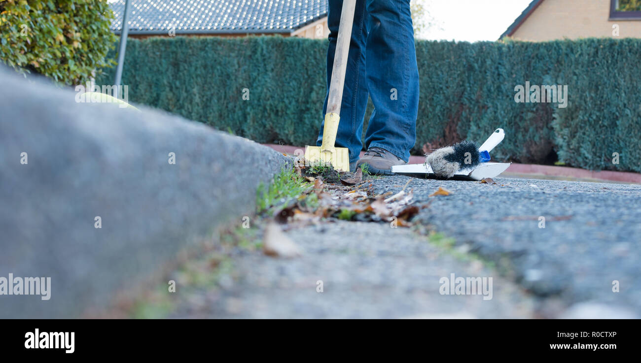 Der Mensch ist die Reinigung der Straße Dachrinne Stockfoto