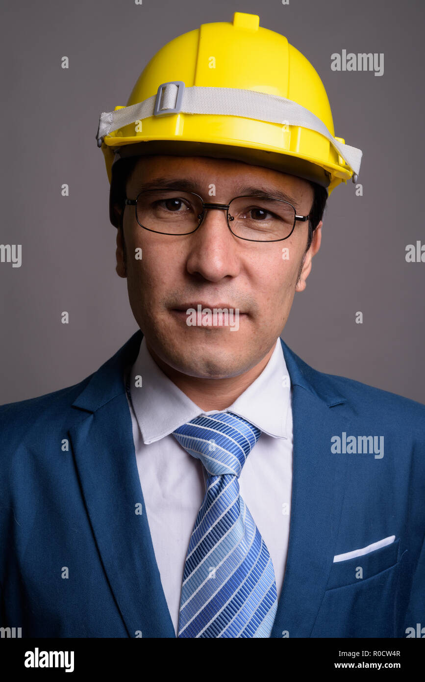 Junge asiatische Geschäftsmann, tragen, hardhat gegen grauer Hintergrund Stockfoto