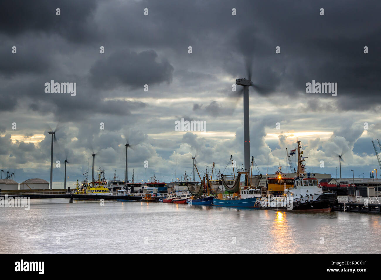 Eemshaven Hafen mit Schiffen bei Sonnenuntergang auf einem dunklen bewölkten Tag, Groningen, Niederlande Stockfoto