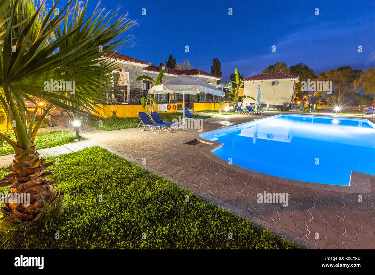 Lange Belichtung Geschossen eines Resorts mit Ziegel Stein chalets und Blue Water Swimming Pool auf einer warmen Nacht Stockfoto