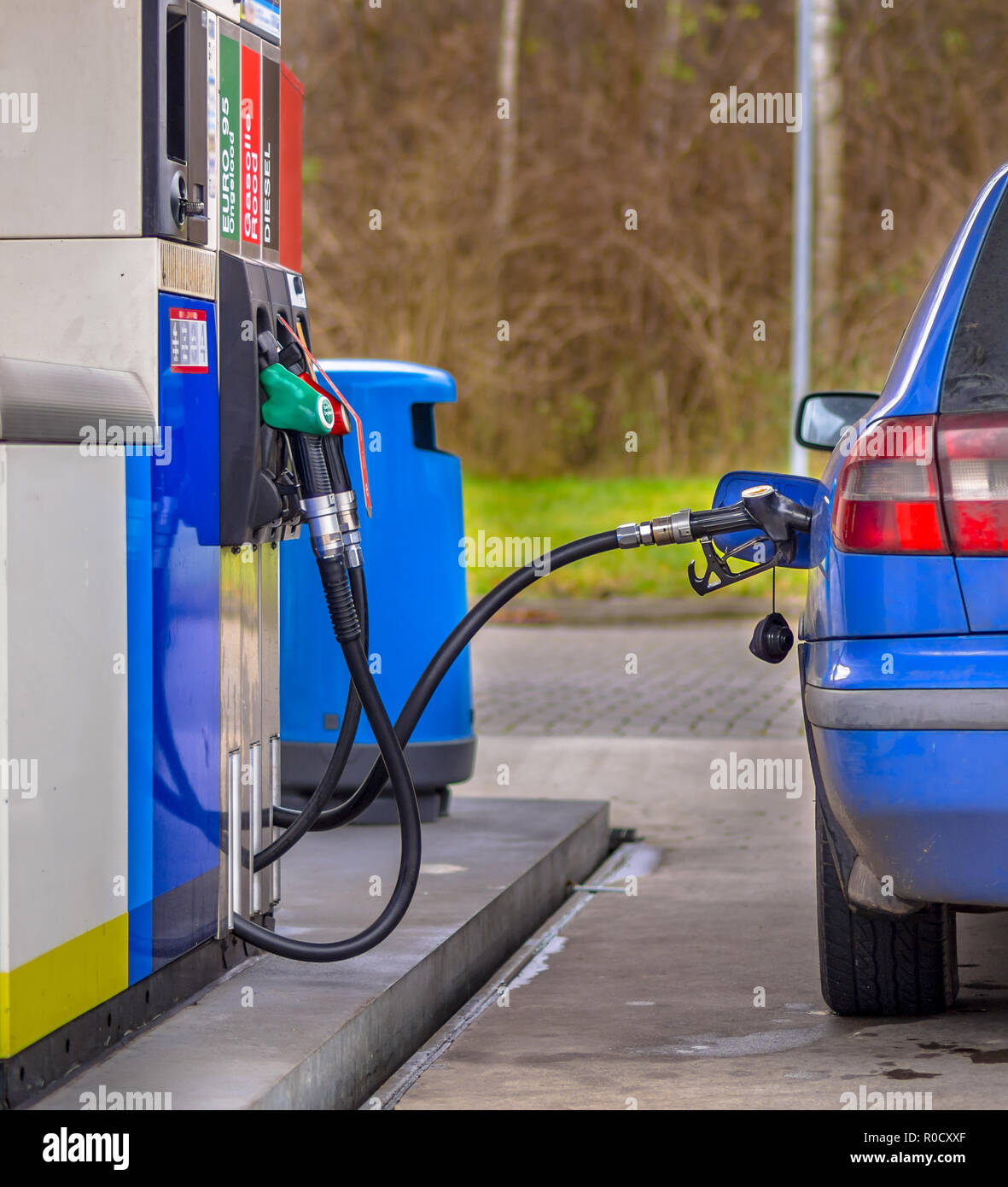 Blaues Auto füllt sich mit Kraftstoff an der Tankstelle gegen überhöhte Preise Stockfoto