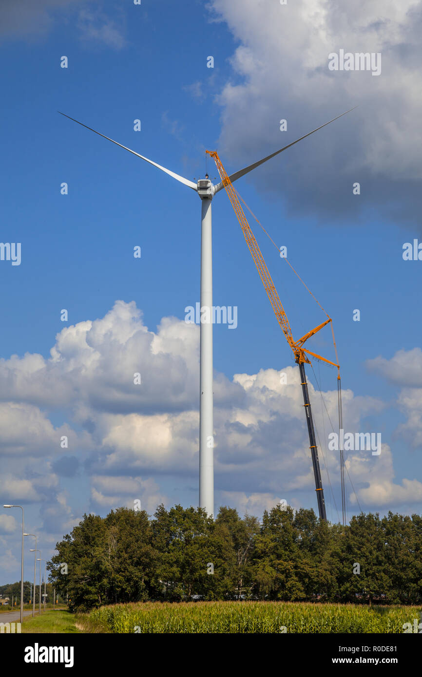 Riesige Windkraftanlage wird von einem großen Kran für Reparatur gewartet Stockfoto