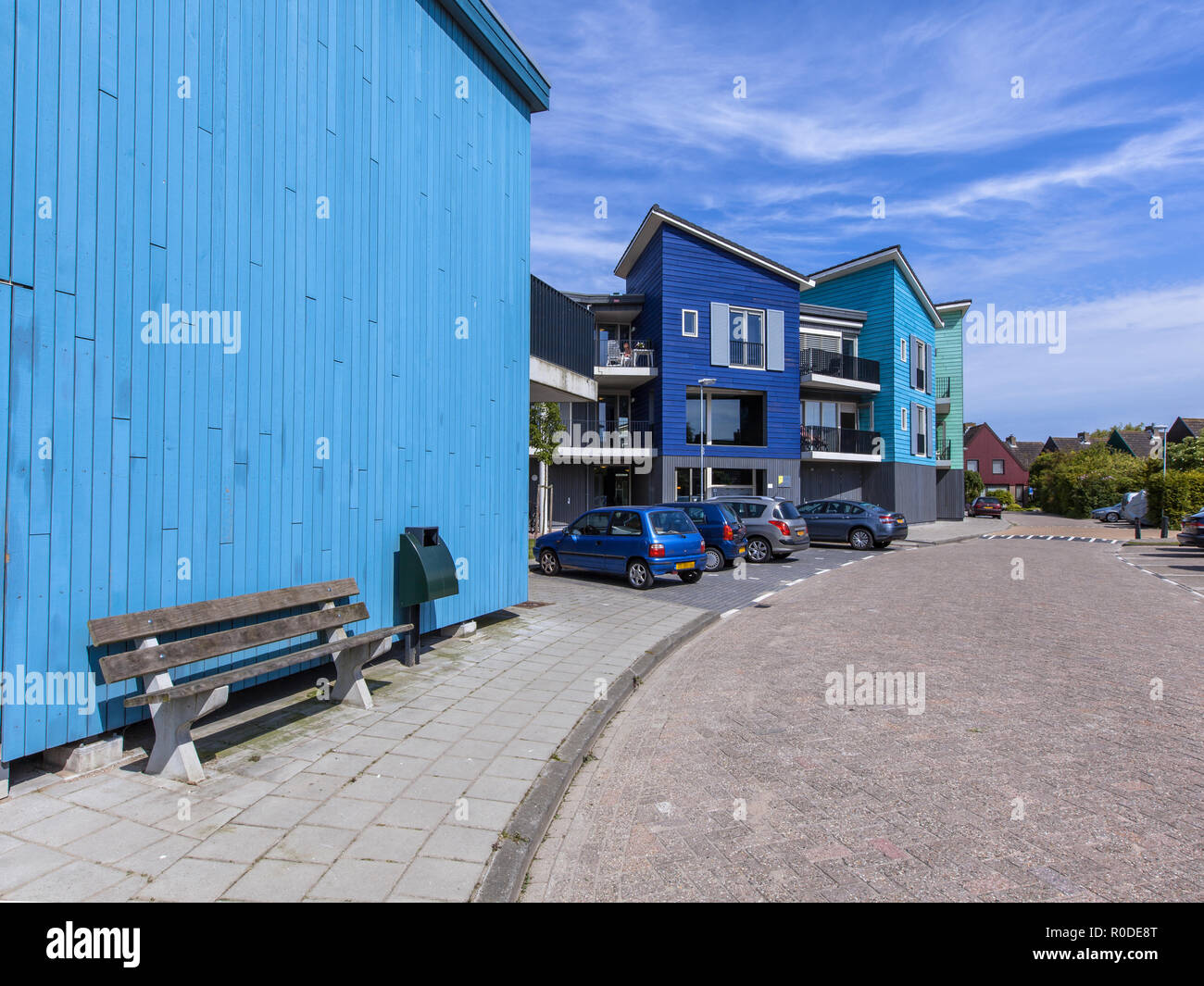 Holzbank in einer Straße mit modernen Häusern. Zeitgenössische Architektur kann auf viele Orte in den Niederlanden wie hier in der Naehe von Amsterdam gefunden werden. Stockfoto