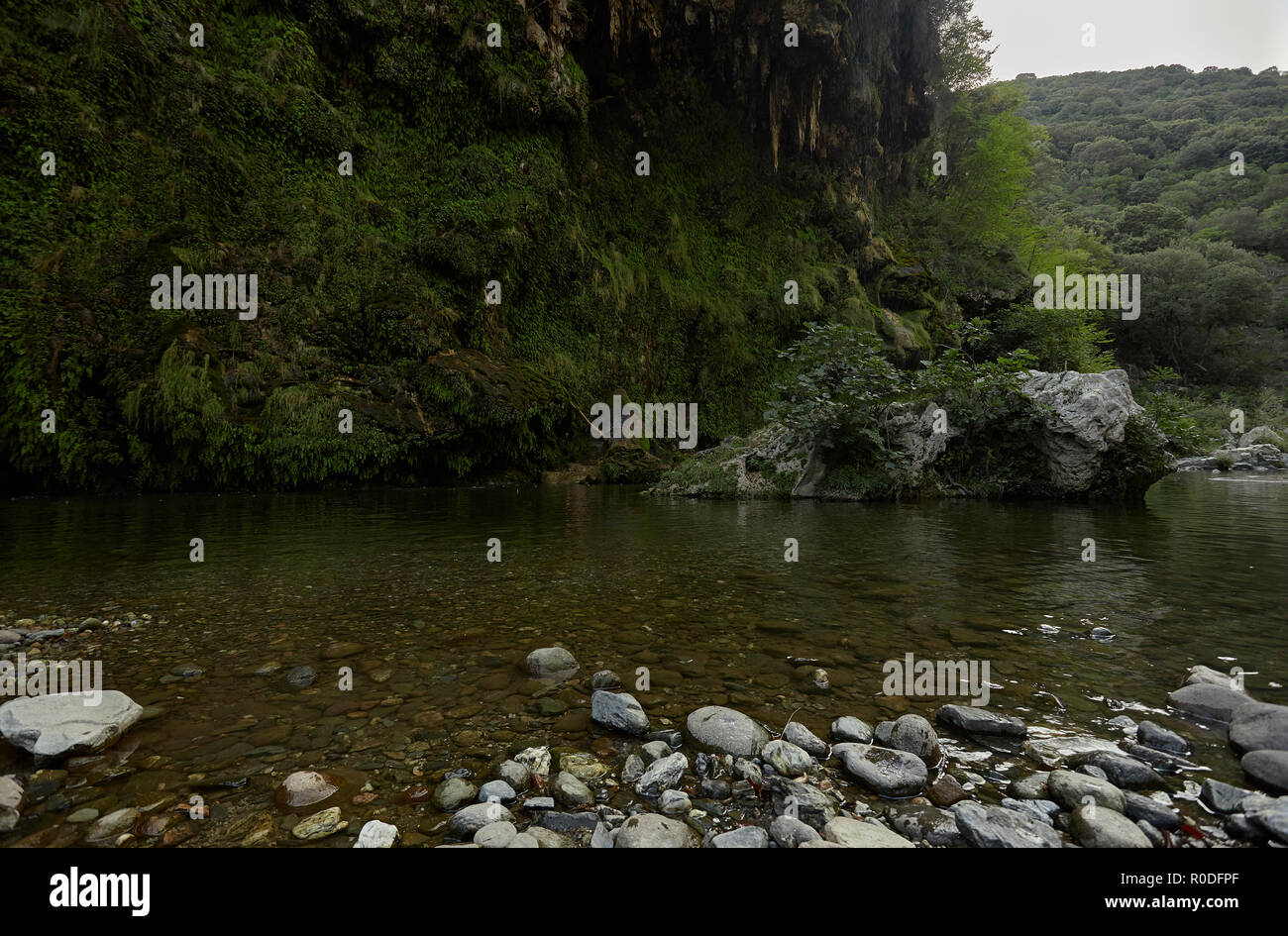 Felswand mit Vegetation bedeckt ist, die Grenze der Wasserlauf in den Bergen mit verschiedenen Felsen, die aus dem Wasser steigen: Die Ansicht von Sa Stid Stockfoto