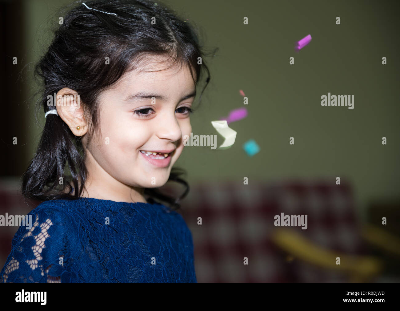 Ein kleines Mädchen mit gebrochenen Zahn Lächeln für die Kamera zum Geburtstag celeberation Stockfoto