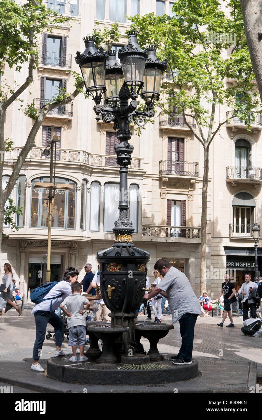 Menschen füllen Plastikflaschen mit frischem Trinkwasser aus einem alten Brunnen in Barcelona, Spanien Stockfoto