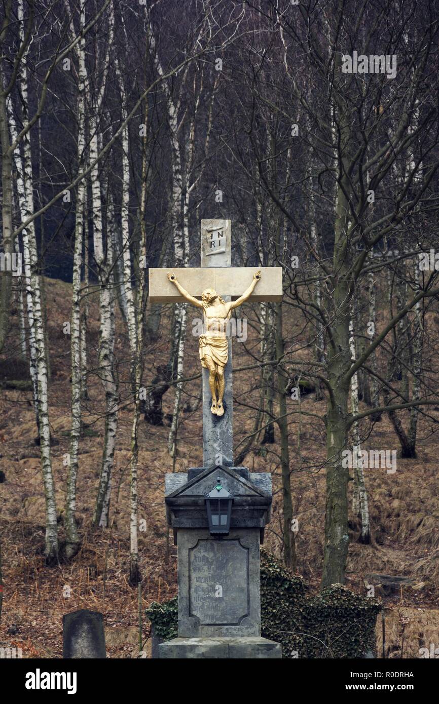 Golden Jesus Christus Kreuzigung Statue, bewölkt Winter dunkler Tag, Birken geheimnisvollen Hintergrund Stockfoto