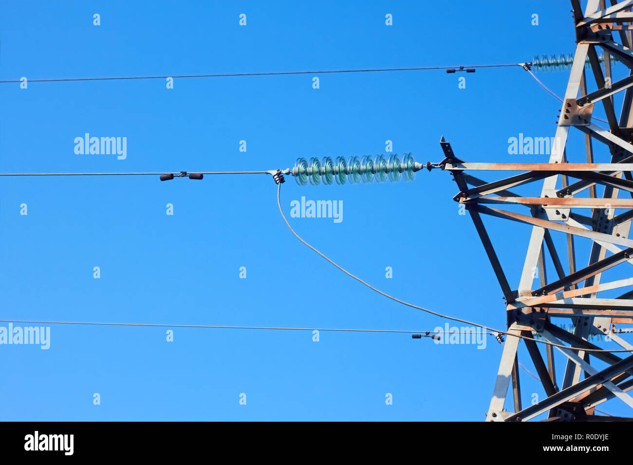 Isolatoren, Drähte und Fragment aus Metall elektrische Turm auf dem Hintergrund des blauen Himmels Stockfoto