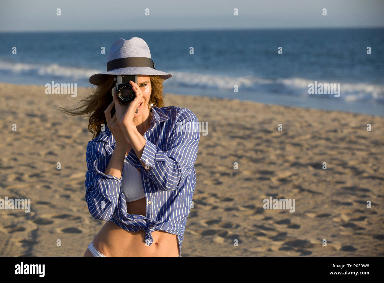Halber Baulänge Portrait von Mid-Adult Frau Suchen durch die Kameralinse am Strand Stockfoto