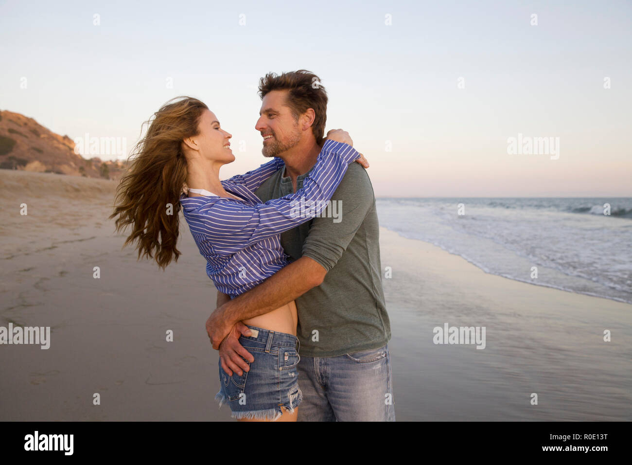 Halber Baulänge sein Porträt der romantischen Mid-Adult Paar in jeder andere Arme am Strand Stockfoto