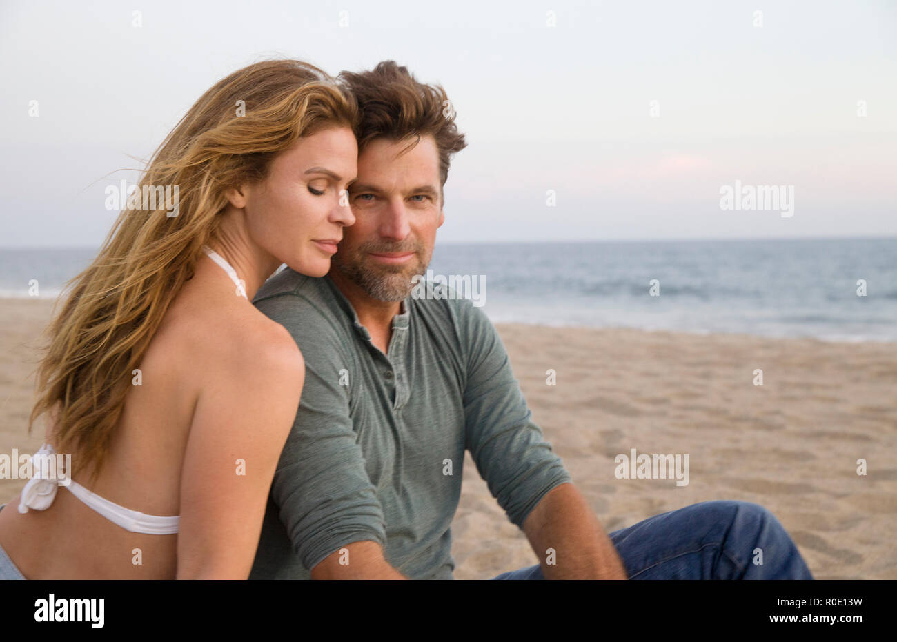 Halber Baulänge Portrait von Mid-Adult Ehepaar am Strand sitzen Stockfoto