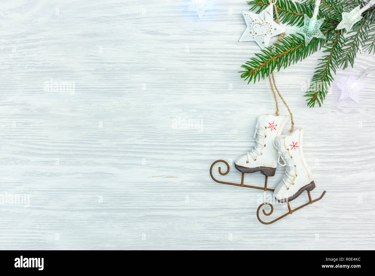 Weiß Holz- Hintergrund mit grünen Fir Tree Branch, dekorative kleine Eis scates und Weihnachtsbeleuchtung. Flach Stockfoto