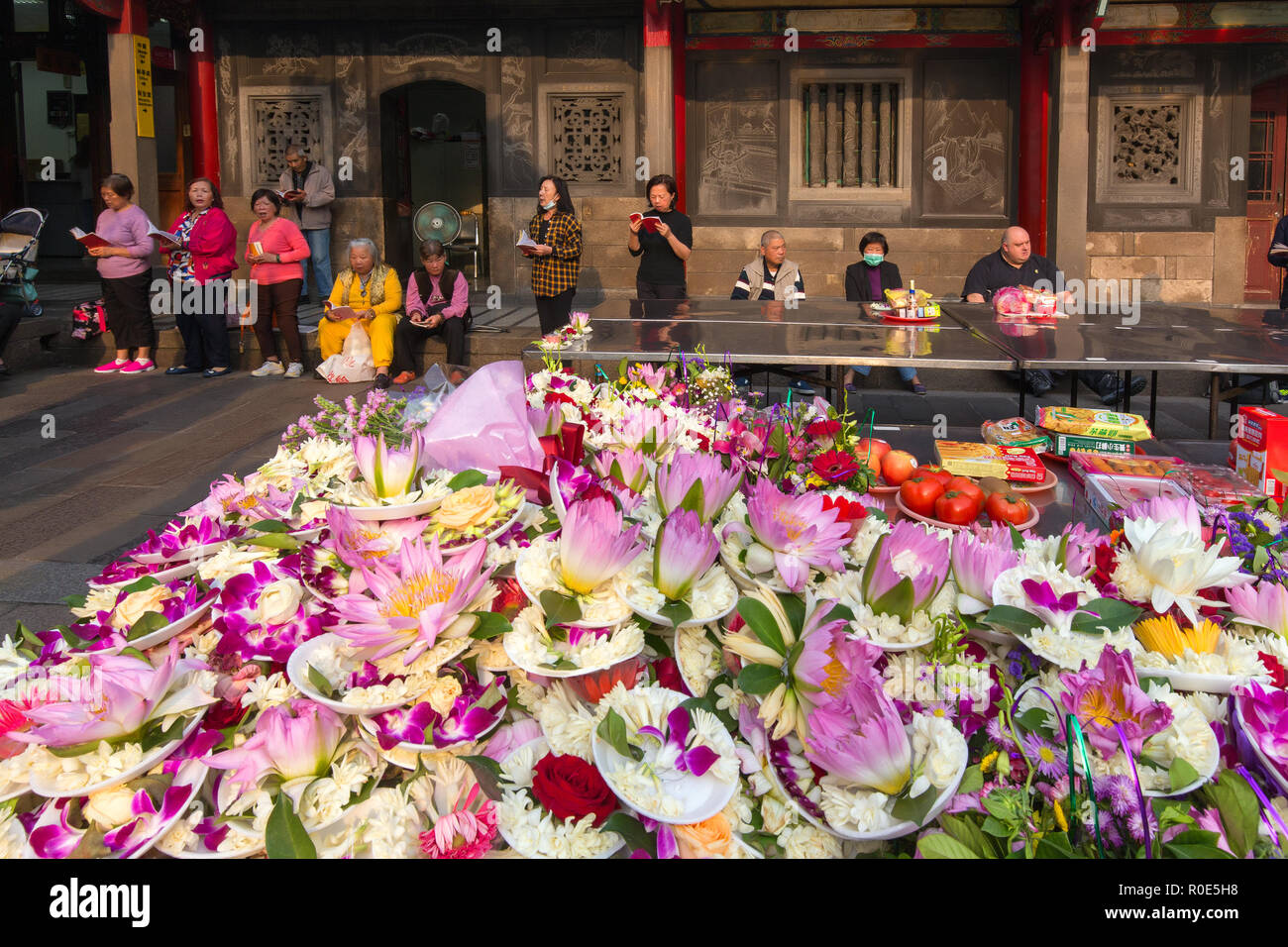 TAIPEI, Taiwan - 28. MÄRZ 2017: Tonnen von Orchideen und Lotus Blumen Angebote und Menschen am Lungshan buddhistischen Tempel beten in Taipei, Taiwan Stockfoto
