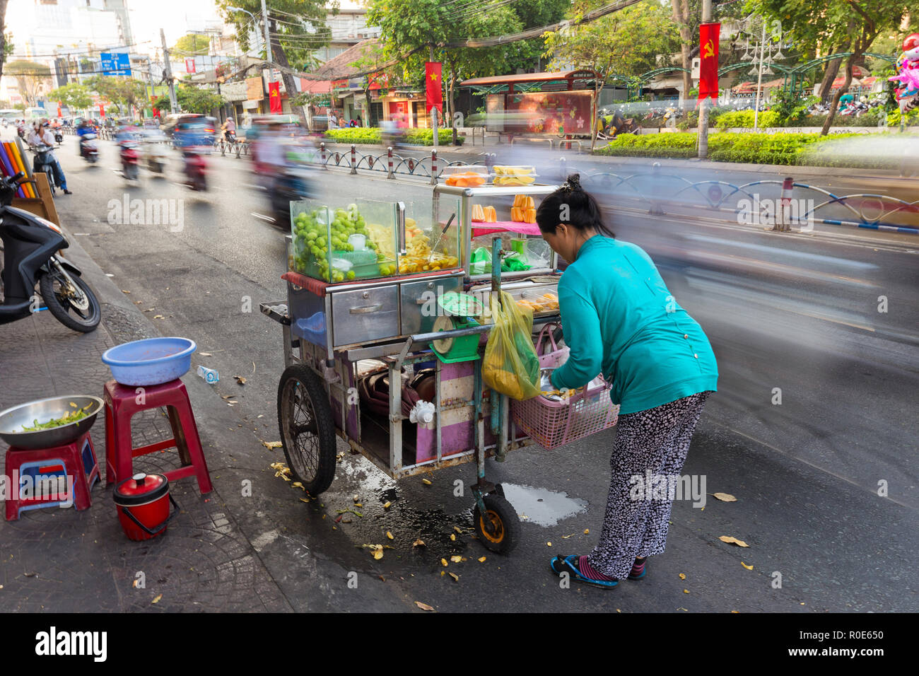 Lange Belichtung auf eine Frucht Verkäufer auf dem Gehweg entlang der Straße in Ho Chi Minh Stadt (Saigon), Vietnam. Stockfoto