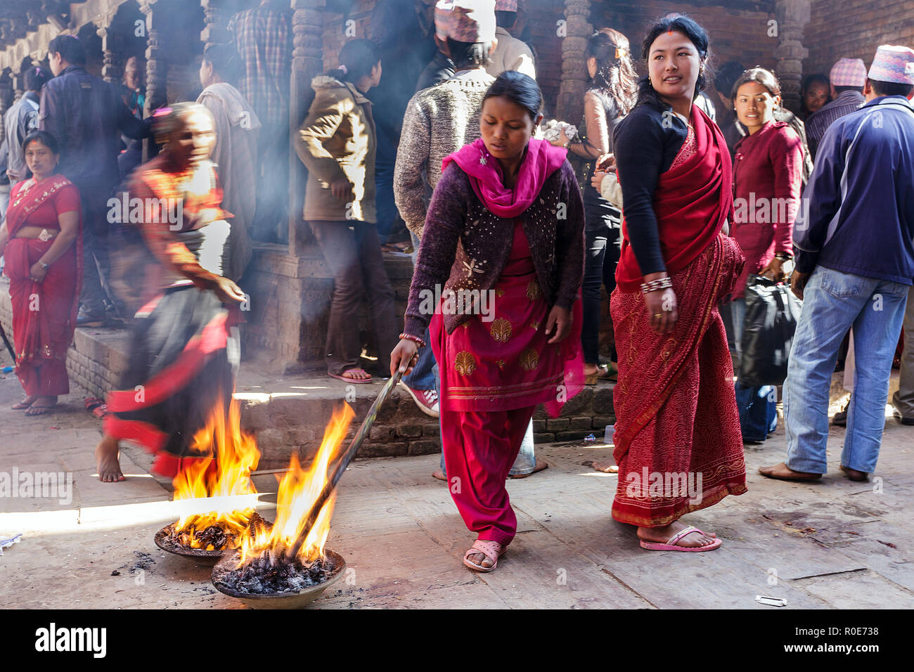BHAKTAPUR, Nepal, November 24, 2010: Frauen sind zündende lange Stöcke in der Straße für einen hinduistischen religiösen Ritual in Bhaktapur, Nepal Stockfoto