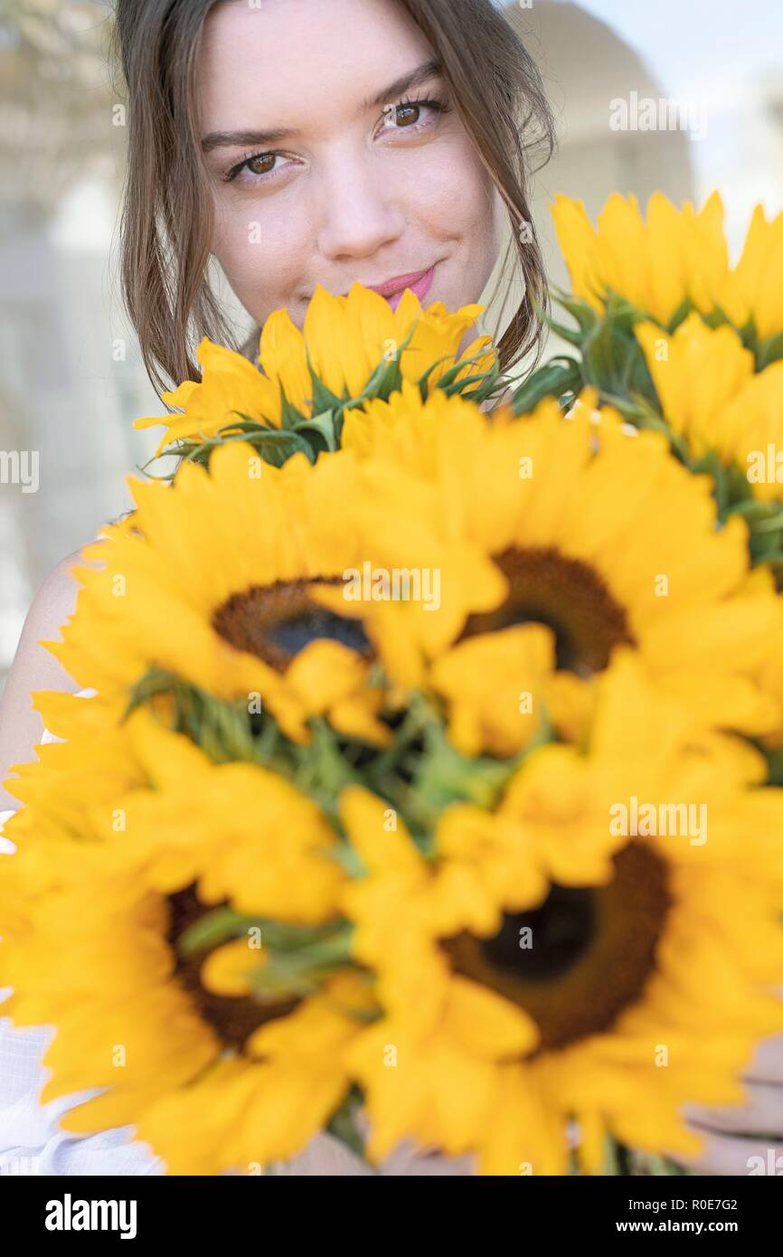 Junge Frau mit Sonnenblumen (Helianthus sp.). Stockfoto