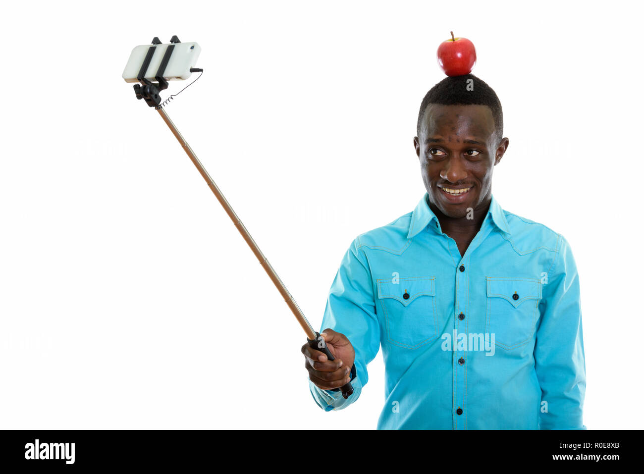 Studio shot der jungen schwarzen afrikanischen Mann glücklich lächelnd mit Rot ap Stockfoto
