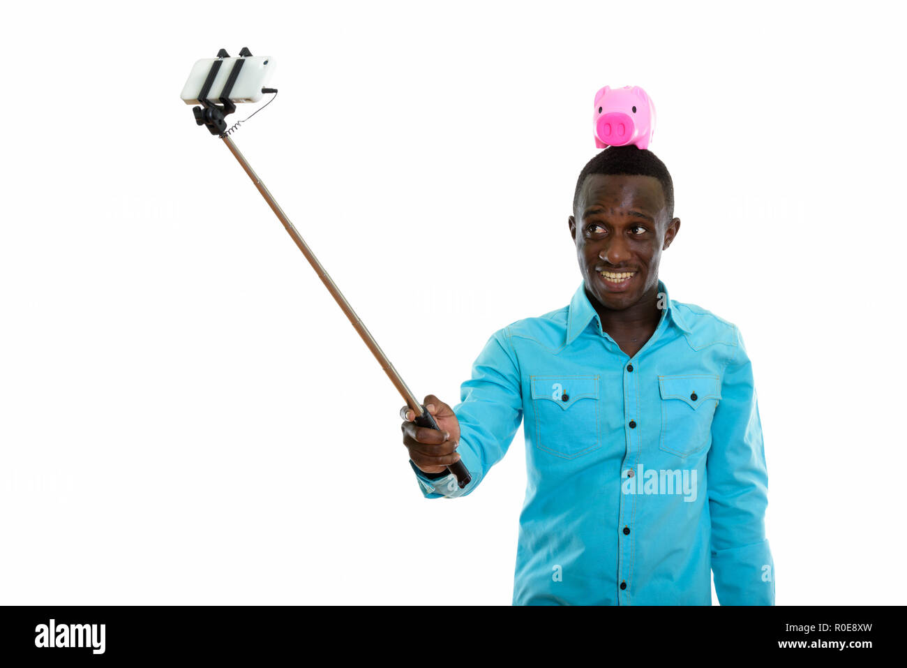 Studio shot der jungen schwarzen afrikanischen Mann glücklich lächelnd mit Piggy Stockfoto