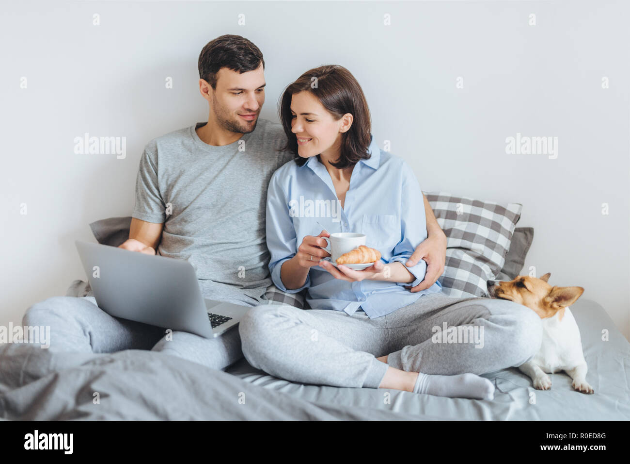 Zärtlich Paar in Liebe im Schlafzimmer Umarmung, warch Film online auf Laptop, frühstücken, genießen Sie heimische Atmosphäre und Ihre bevorzugten Pe Stockfoto