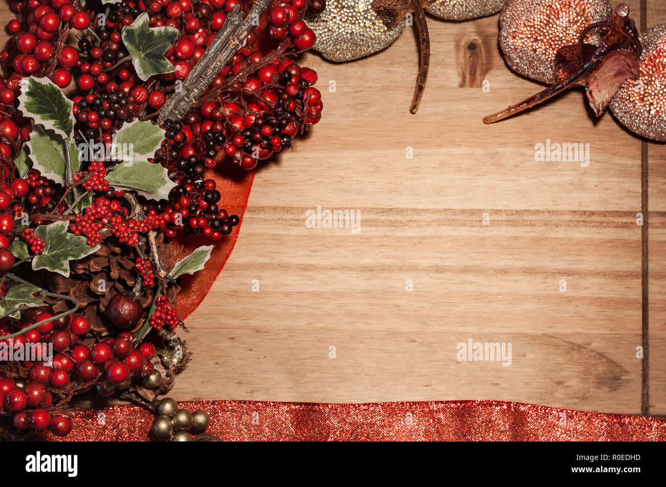 Weihnachten thematische Rahmen mit holly bush und Weihnachtsschmuck auf einer hölzernen Oberfläche mit Platz für Text. Weihnachten Konzept. Rot. Gold. Grün Stockfoto