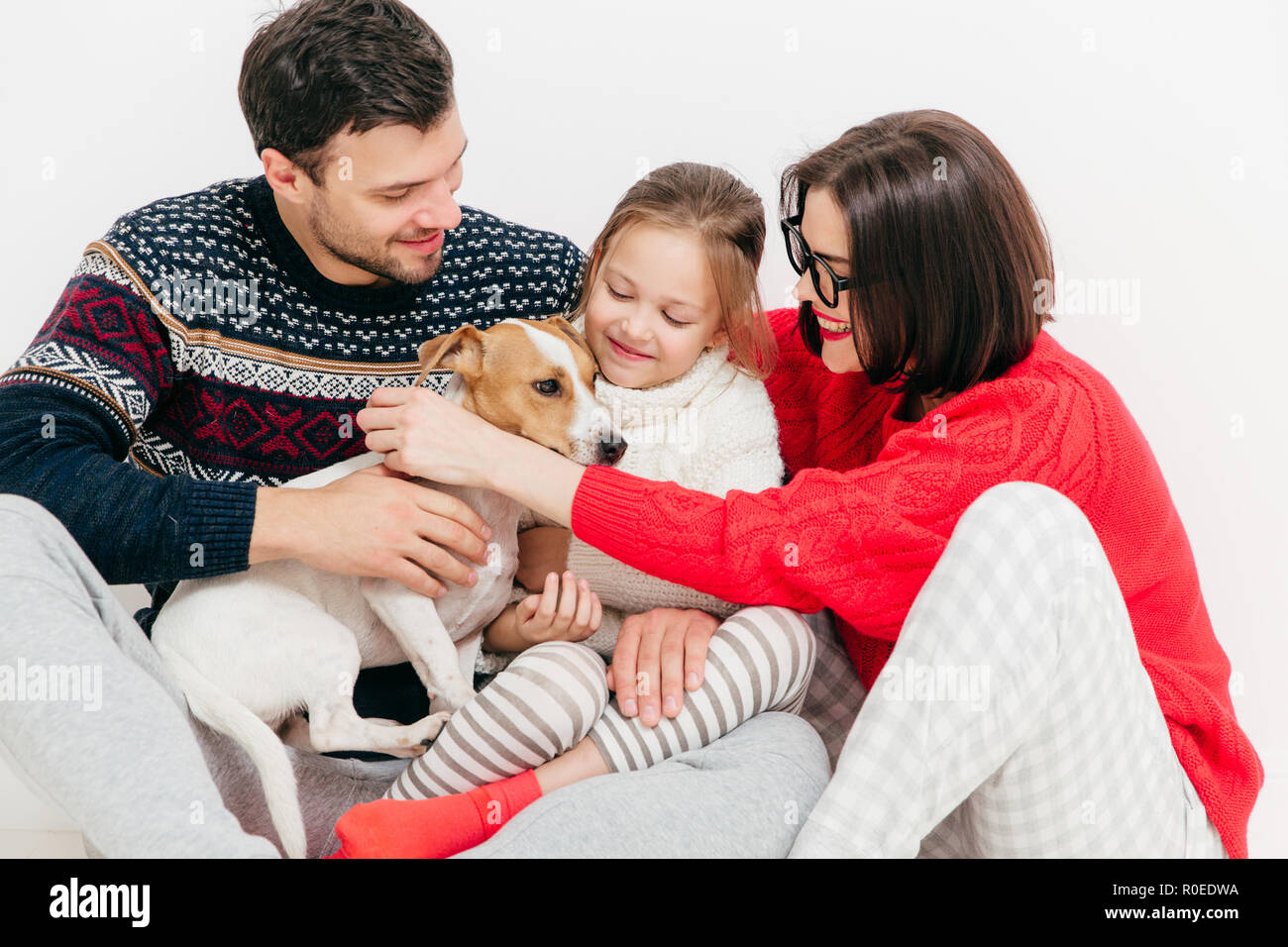 Foto von freundlichen Familie sich umarmen und ihr Hund flacher, Spaß haben, stellen gemeinsam gegen den weißen Hintergrund. Kleine weibliche Kind, ihr Vater, m Stockfoto